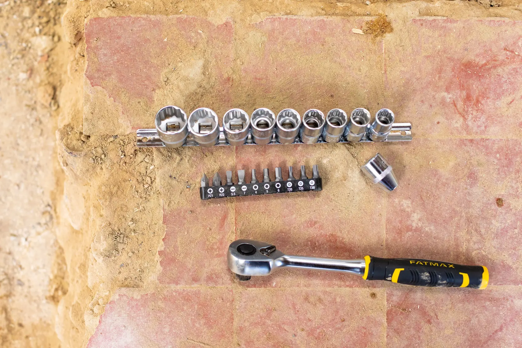 STANLEY FMMT82680-0 set di bussole e inserti con manico a cricchetto, varie bussole e inserti su superficie in mattoni, vista dall'alto.