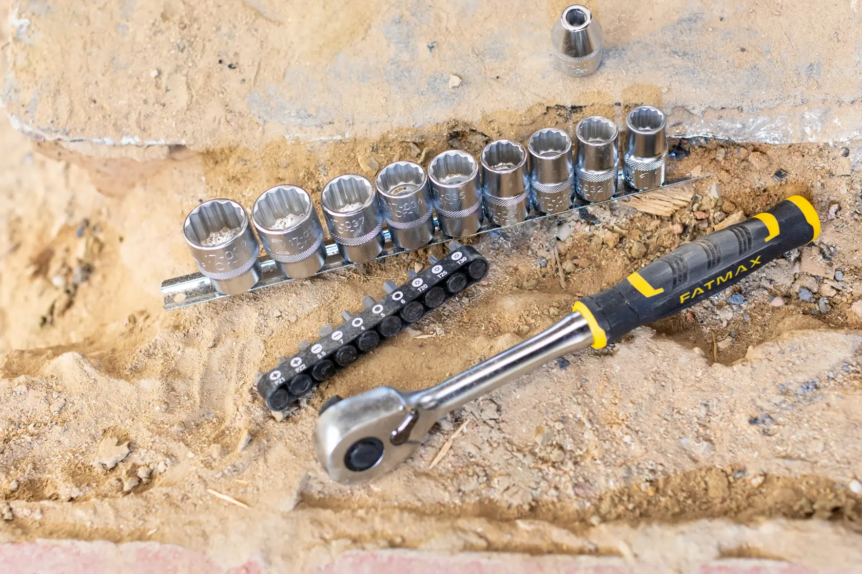 STANLEY FMMT82681-0 socket wrench set with ratchet and sockets on sandy surface, FatMax branding visible.