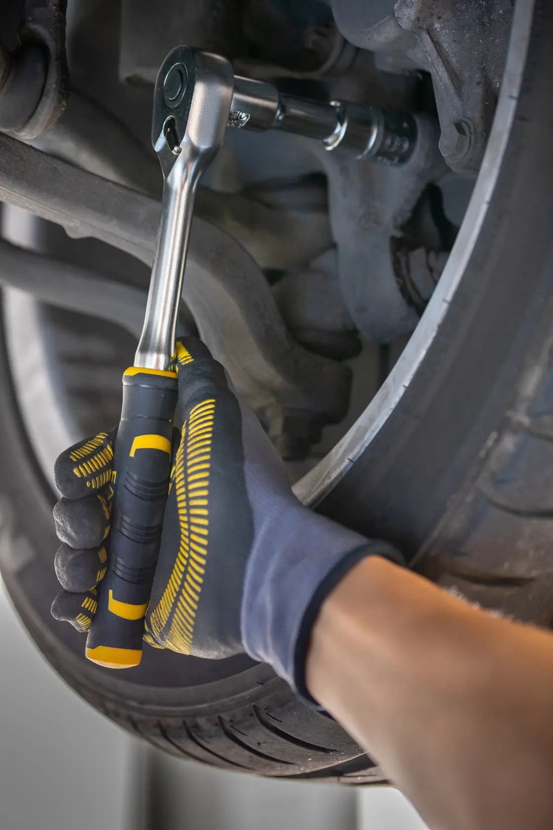 STANLEY FMMT82681-0 ratchet wrench used on car wheel, close-up of gloved hand gripping tool.