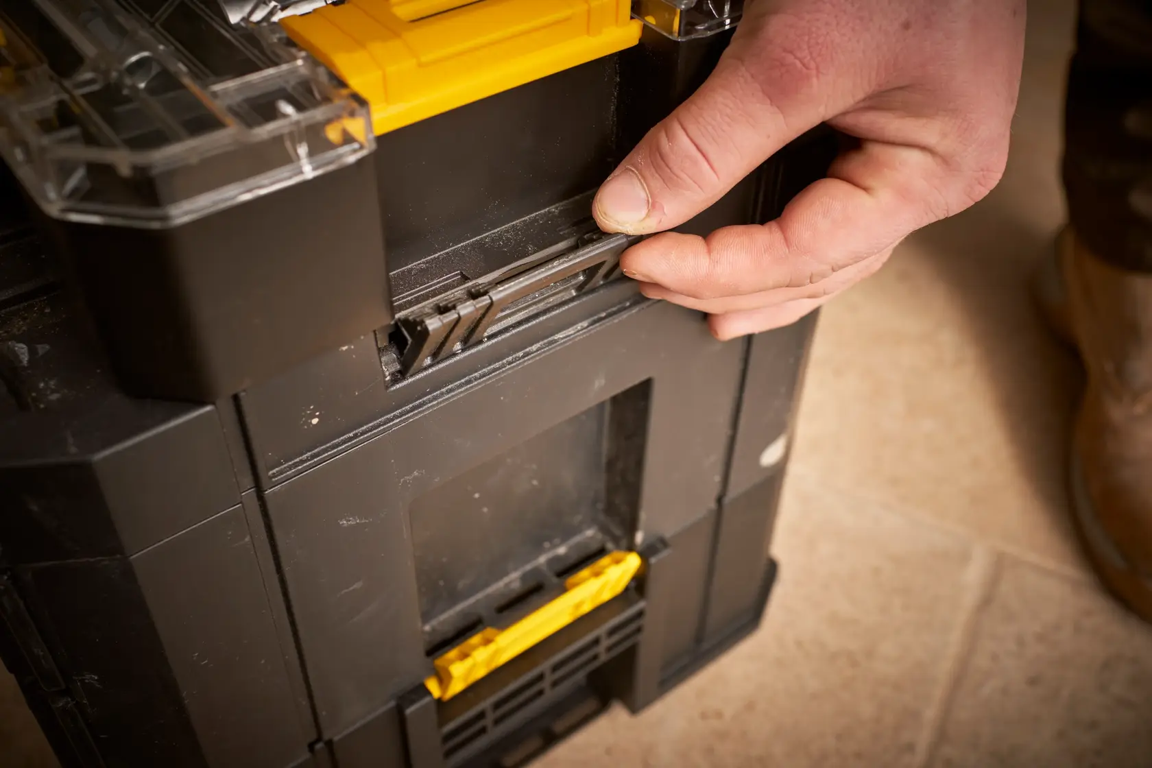 STANLEY FMMT98106-1 black toolbox with yellow latches, close-up of hand operating locking mechanism.