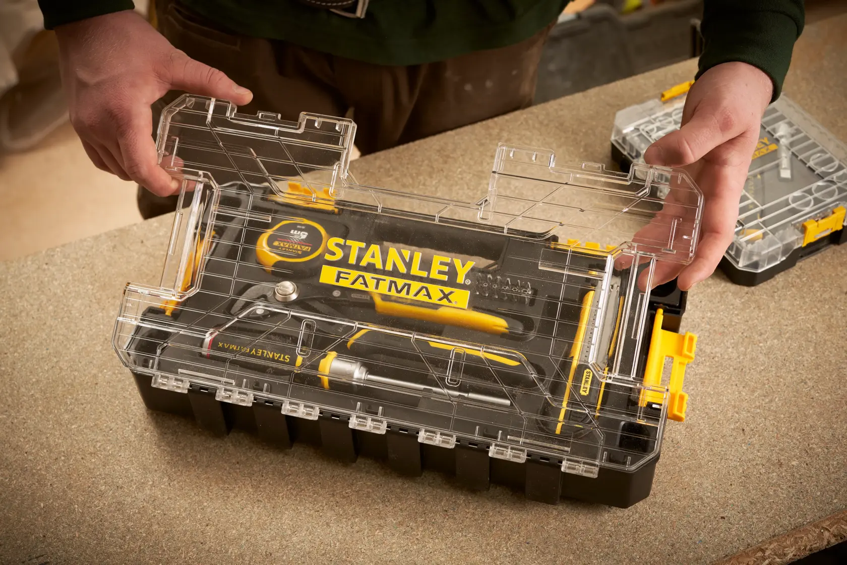 STANLEY FMMT98106-1 toolkit with transparent lid on workbench, featuring yellow and black hand tools.