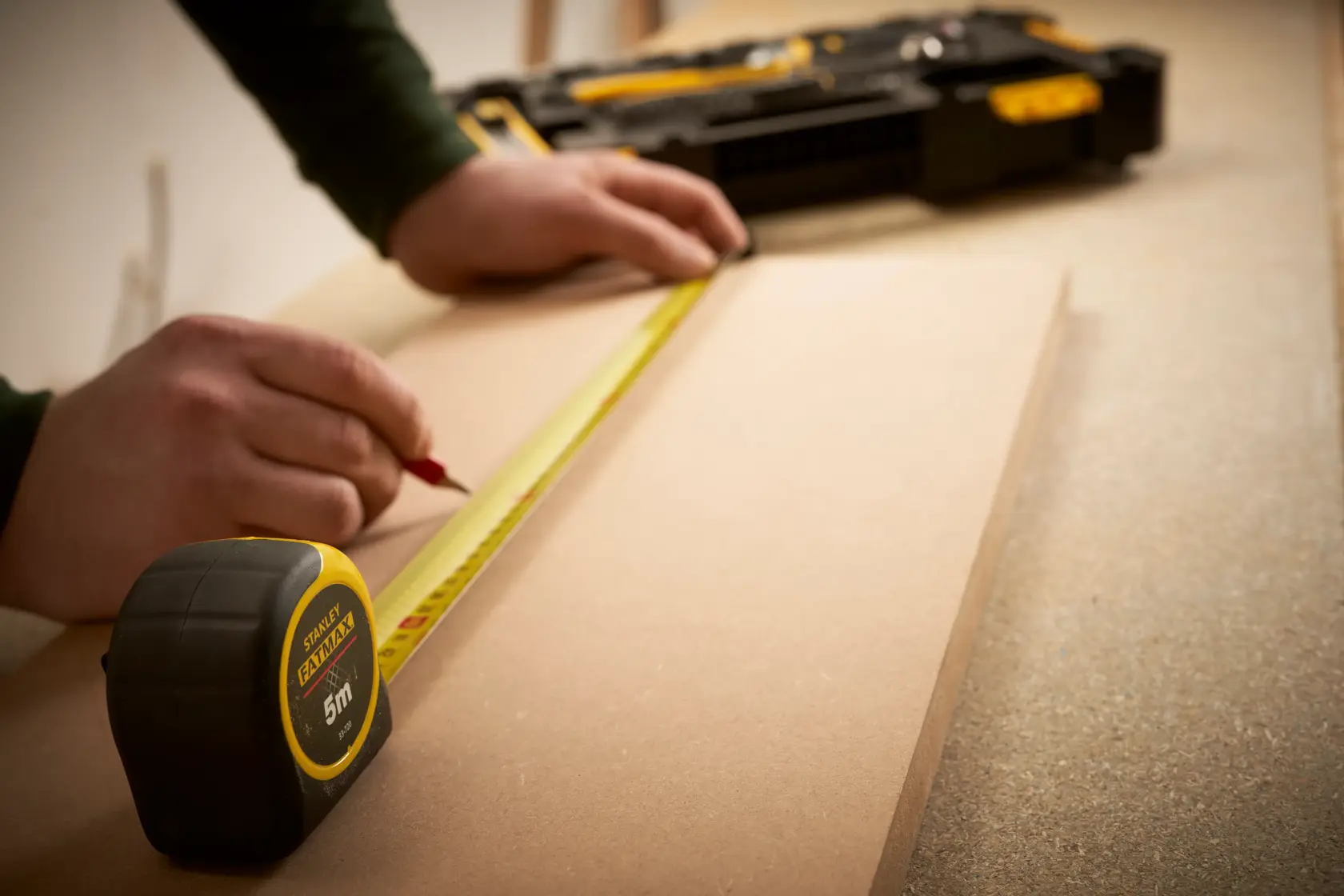 STANLEY FMMT98106-1 tape measure on wood with hand marking measurements, workshop setting.