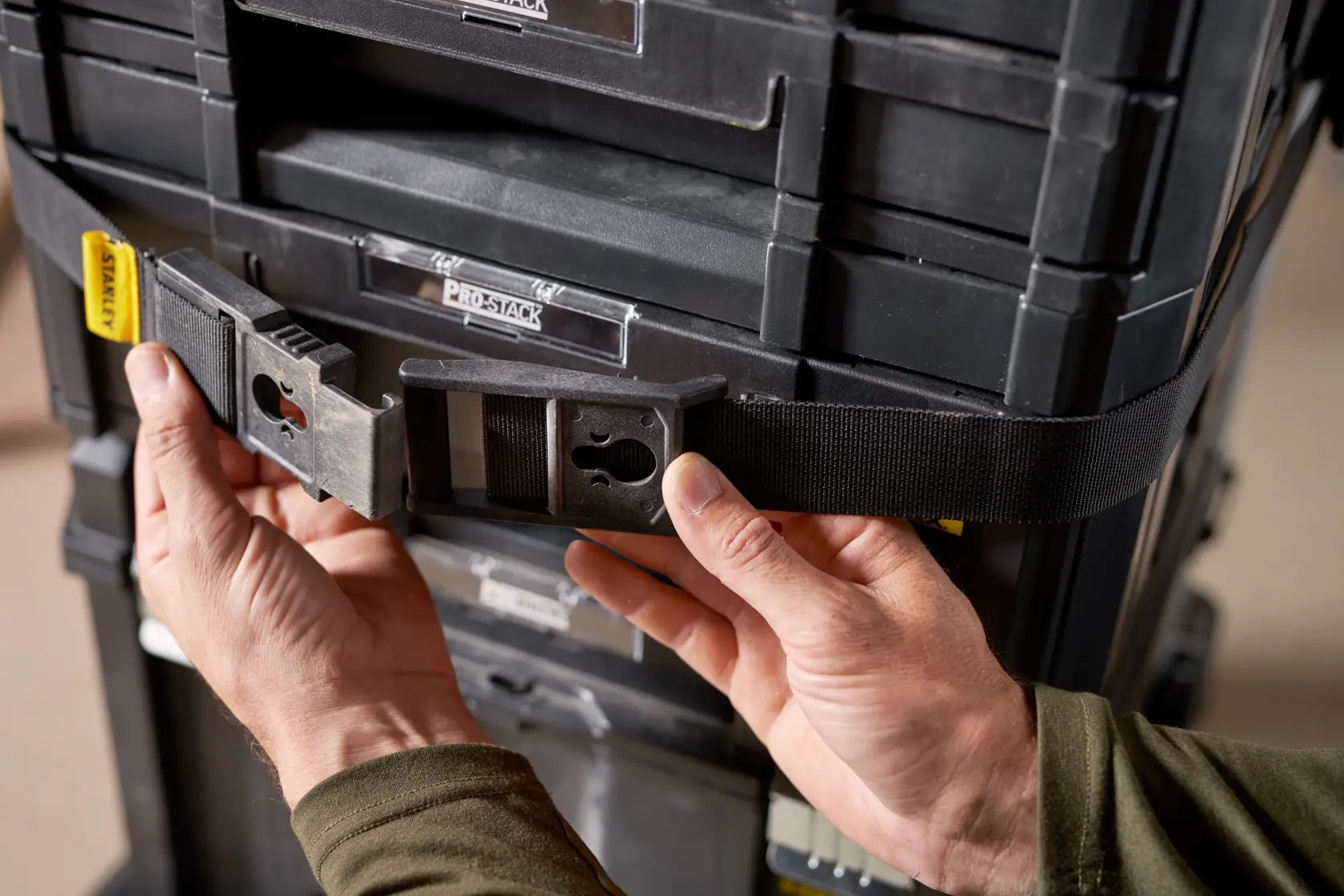 Photo of STANLEY FMST1-72363 tool storage strap with buckle securing black modular toolboxes, close-up view.
