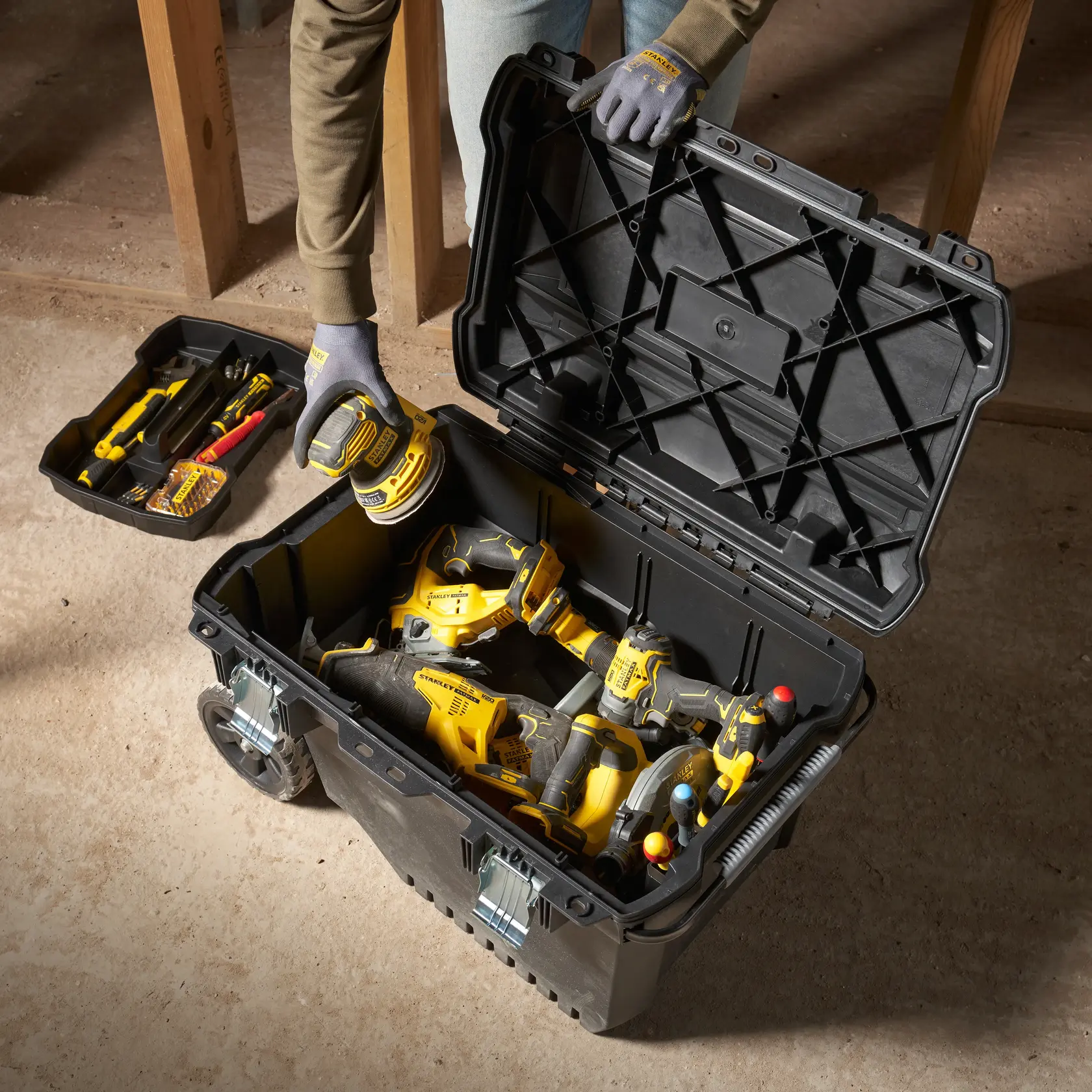 STANLEY FMST1-73601 boîte à outils ouverte avec divers outils électriques, vue du dessus sur sol d’atelier.