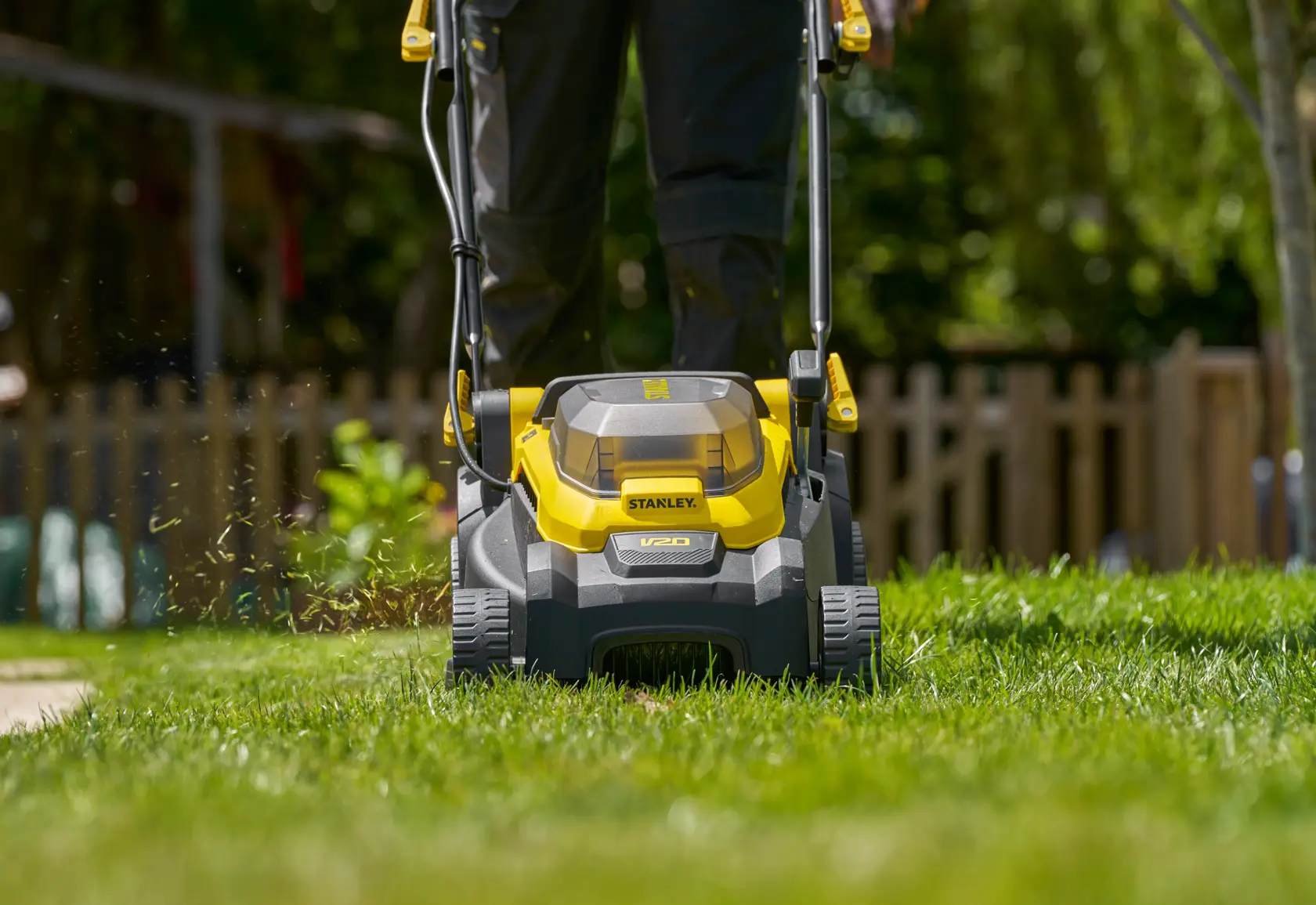 Photo of STANLEY SCMWP3401M1-XE cordless lawn mower on grass, front view showing yellow and black design.