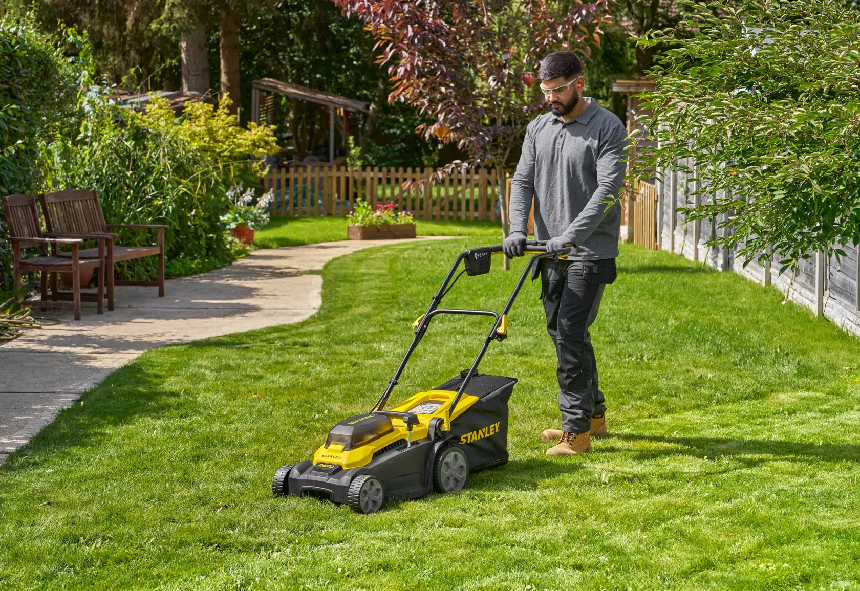 Photo of STANLEY SCMWP3701M2 lawn mower in use on a green lawn, outdoor garden setting.