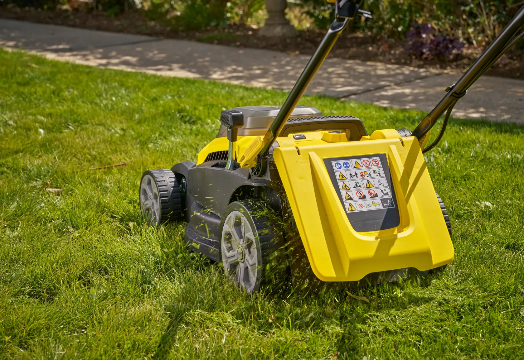 Photo of STANLEY SCMWP3701M2 lawn mower side view on grass with yellow and black body and large rear wheels.