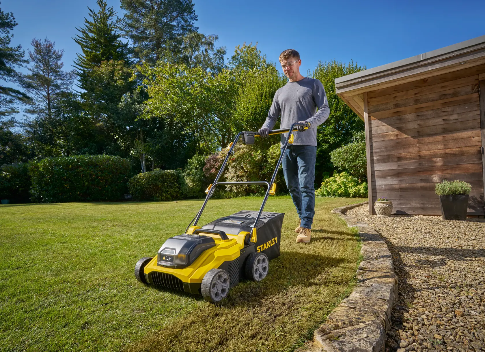 STANLEY SCOEP3801N scarificateur de pelouse utilisé sur une pelouse de jardin, vue extérieure avec abri.
