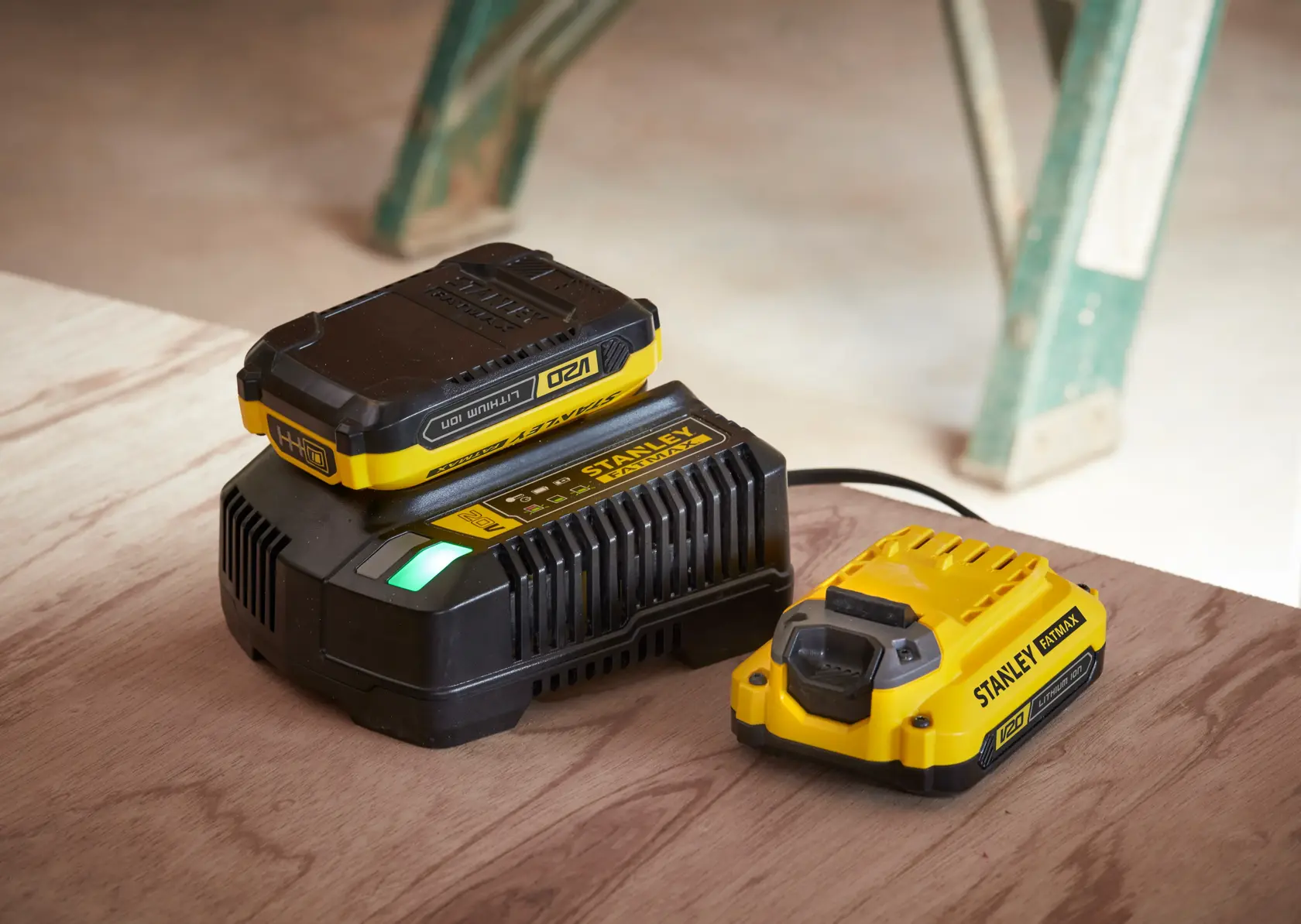 STANLEY SFMCB14 chargeur de batterie et batterie, jaune et noir, vue latérale sur surface en bois.