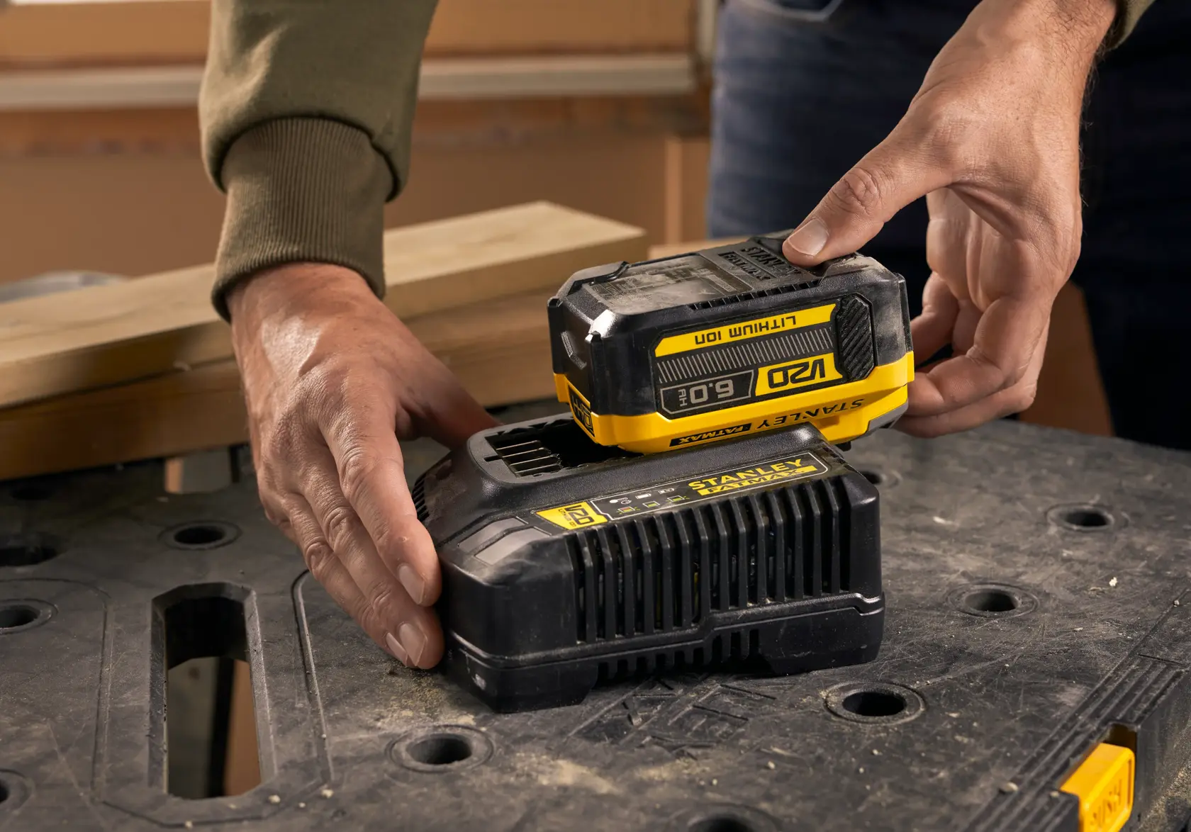 Batterie STANLEY SFMCB206 placée sur un chargeur, gros plan sur surface de travail noire.
