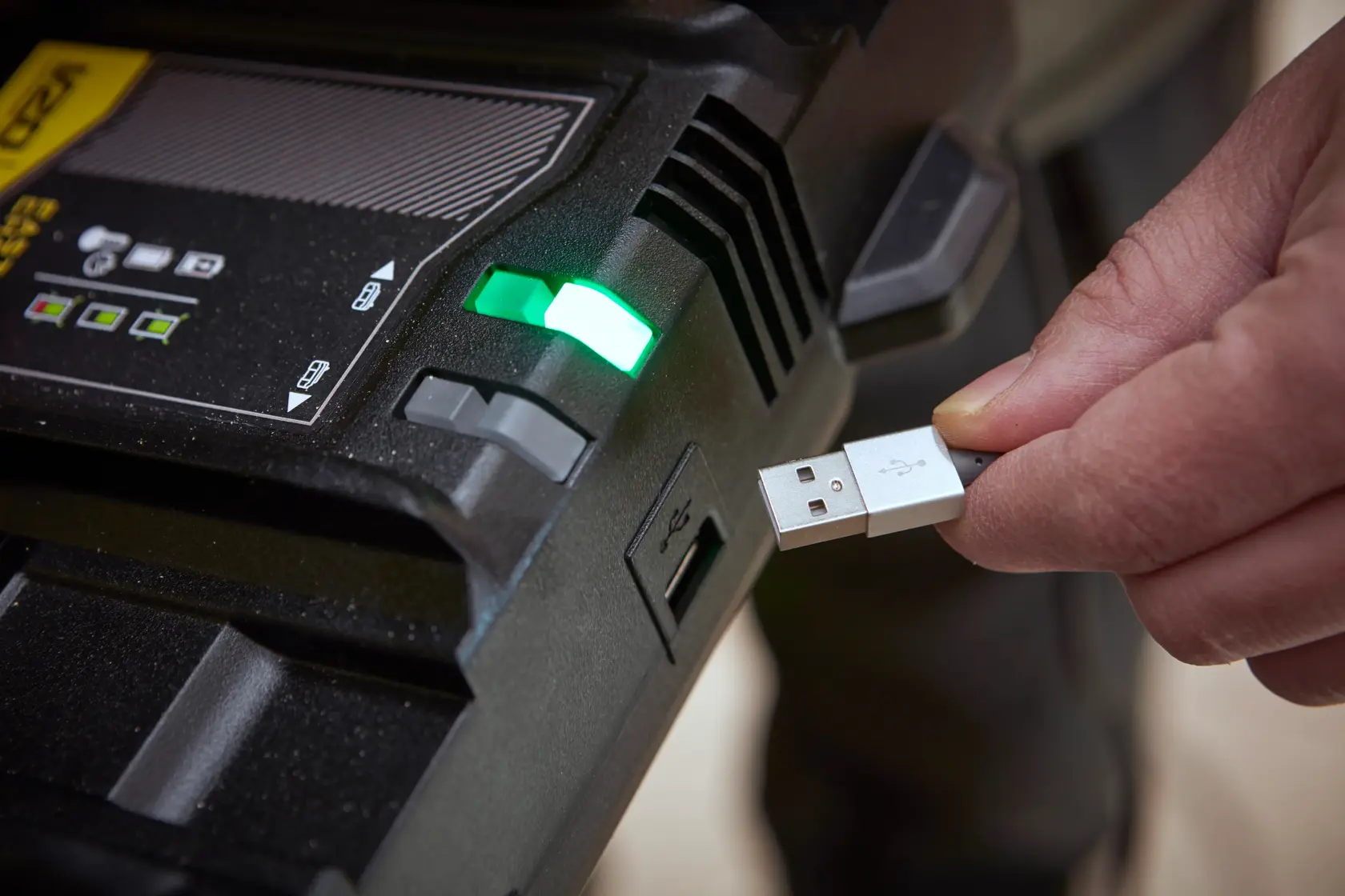 Caricabatterie STANLEY SFMCB24 con indicatore verde e persona che collega cavo USB, primo piano.
