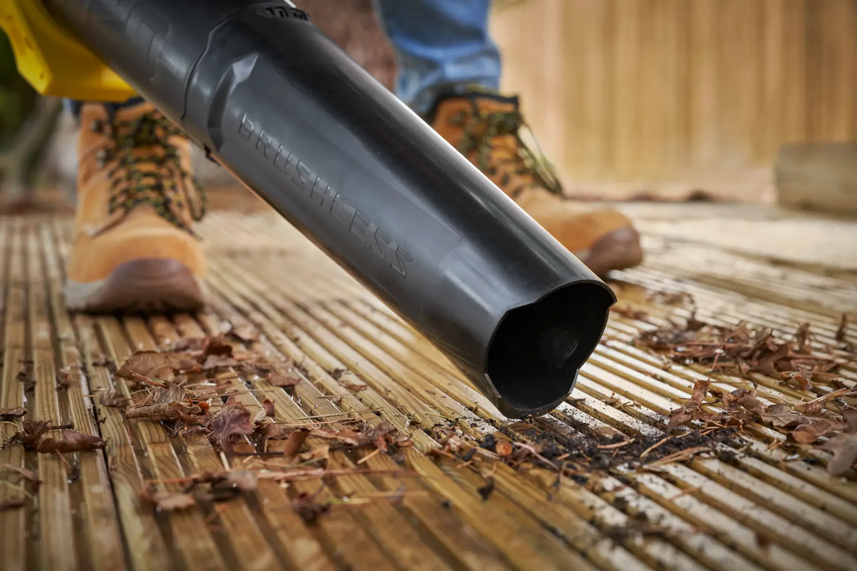Ugello del soffiatore STANLEY SFMCBL730M1 in uso su decking in legno, soffia foglie secche e detriti.