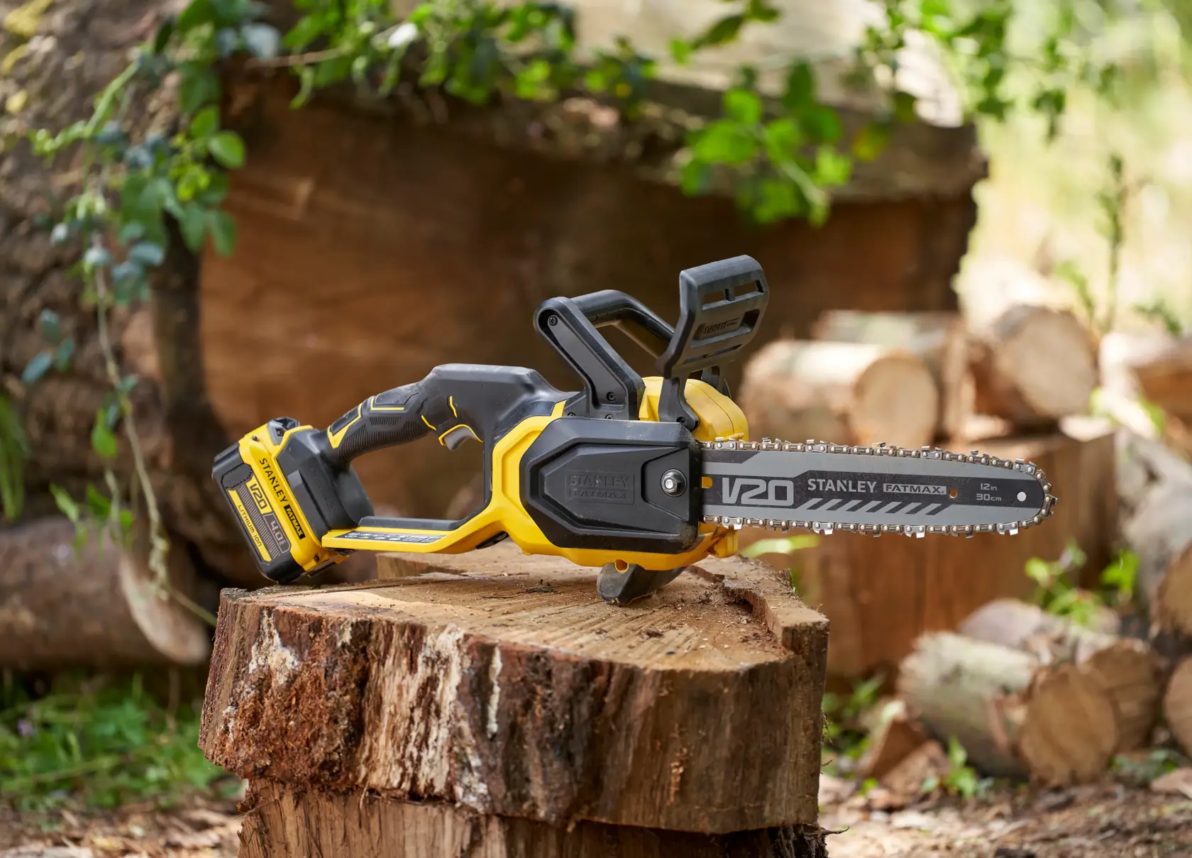 STANLEY SFMCCS730B tronçonneuse sans fil jaune et noire posée sur une souche d’arbre en extérieur.