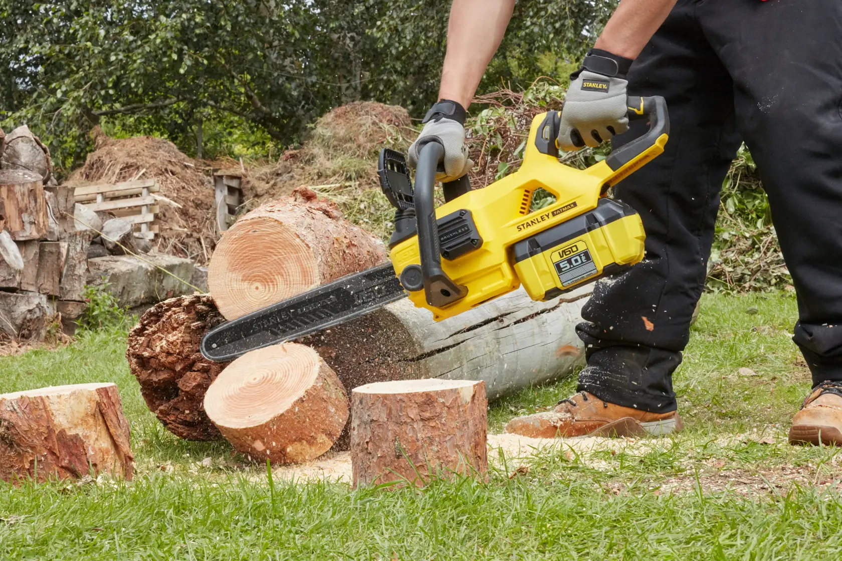 STANLEY SFMCCSB664B chainsaw cutting logs outdoors, showing yellow body and black blade.