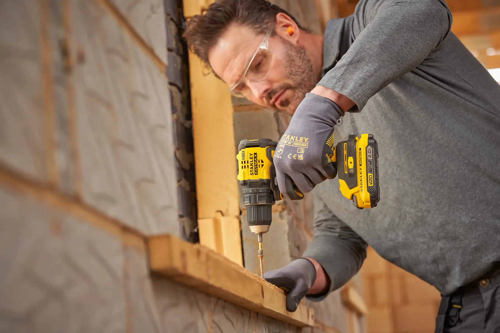Photo d'une personne utilisant une perceuse sans fil STANLEY SFMCD714B-XJ, vissant dans du bois sur un chantier.
