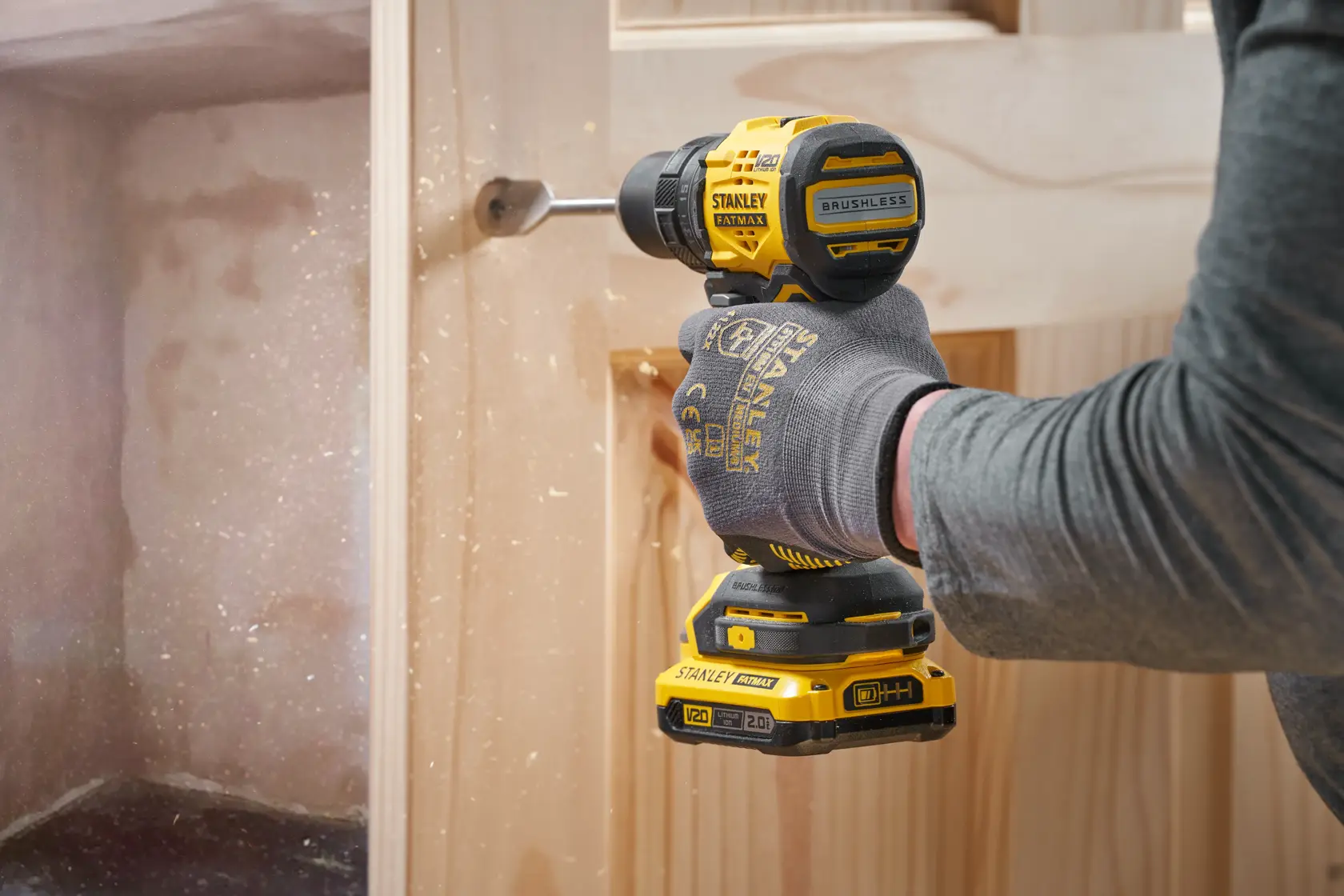 Perceuse sans fil STANLEY SFMCD714B-XJ en utilisation, perçage du bois, vue latérale, outil électrique jaune et noir.