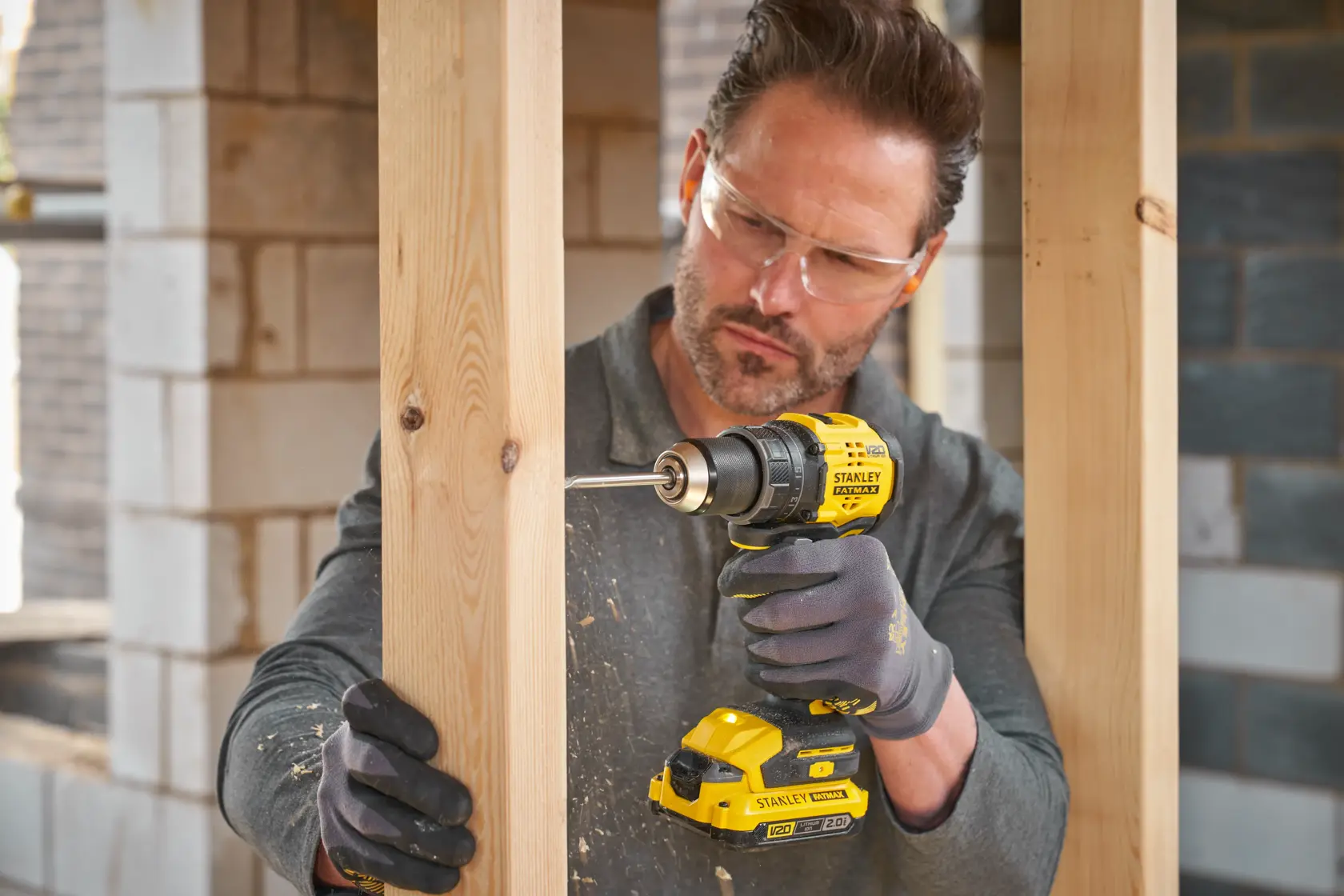 Photo de la perceuse sans fil STANLEY SFMCD714B-XJ utilisée pour percer du bois sur un chantier.