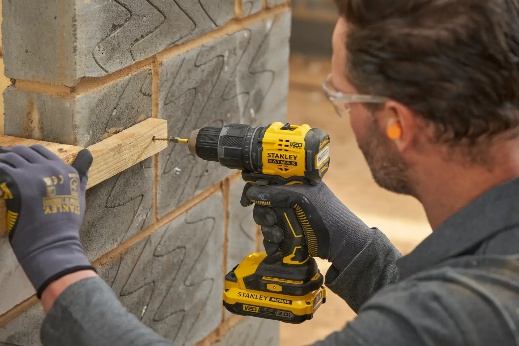 Perceuse sans fil STANLEY SFMCD716B-XJ utilisée pour visser du bois sur un mur en béton.
