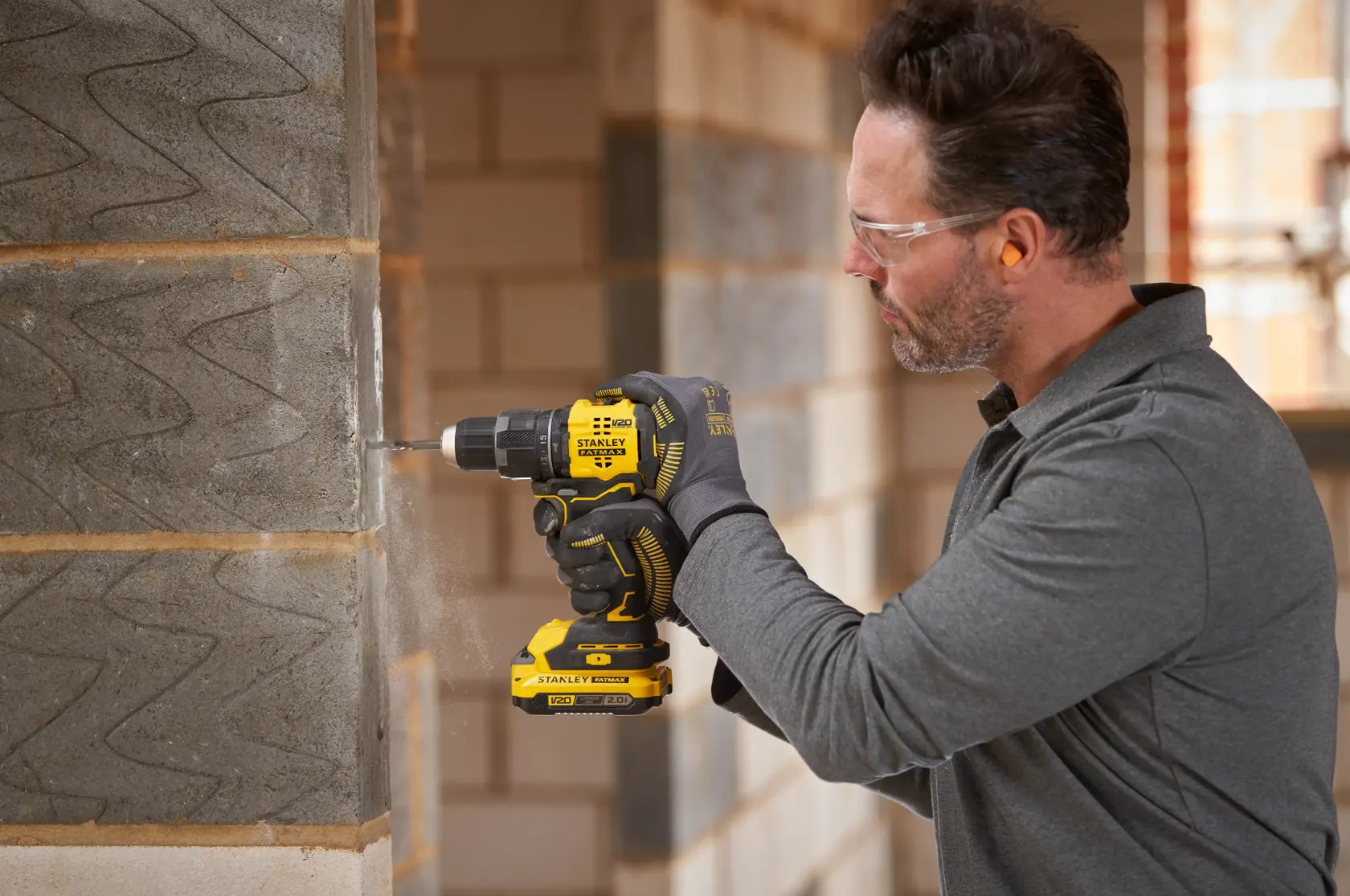 Photo de la perceuse sans fil STANLEY SFMCD716B-XJ utilisée pour percer un mur en béton sur un chantier.