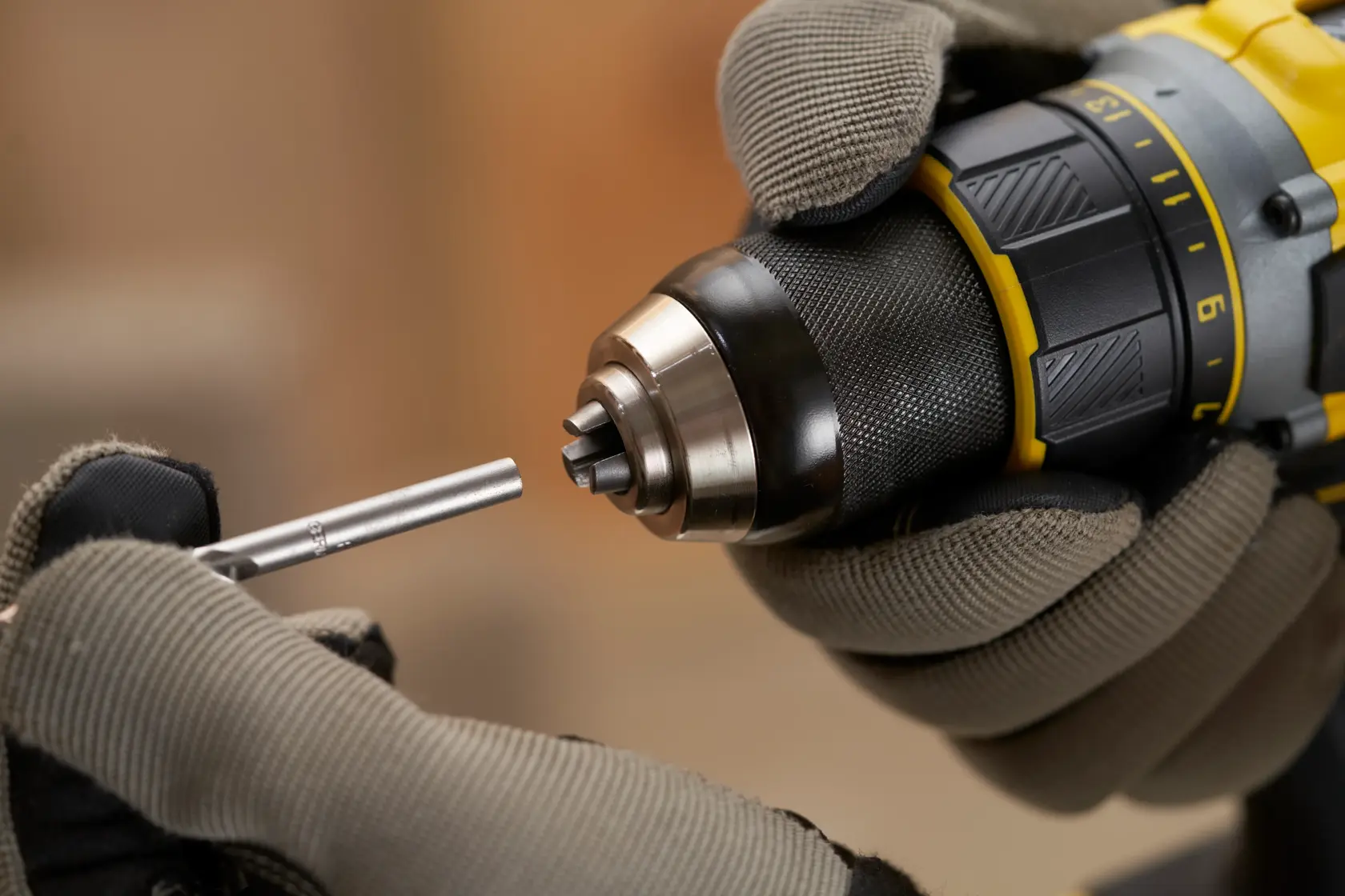 STANLEY SFMCD720D2K drill held in gloved hands, inserting a drill bit, product close-up angle.