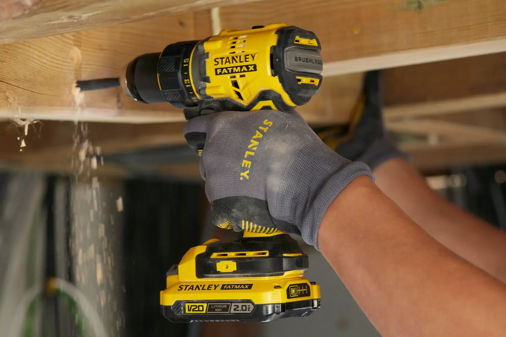 STANLEY SFMCD720D2K cordless drill in use drilling wood, yellow and black, close-up action shot.
