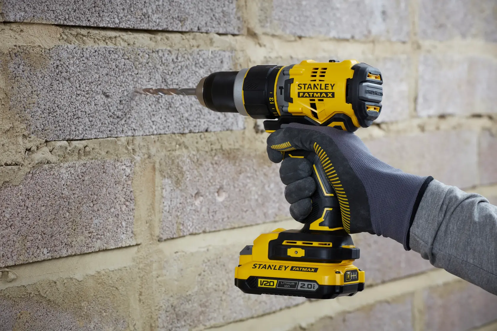 STANLEY SFMCD721B cordless drill in use on masonry wall, close-up side angle.