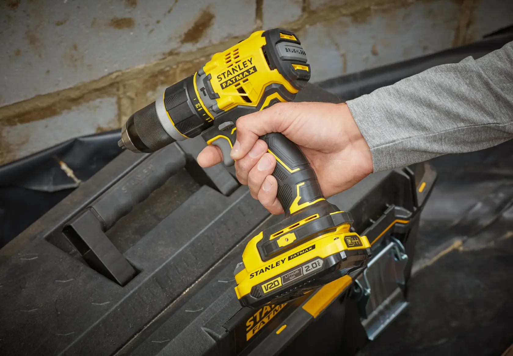 Photo of STANLEY SFMCD721D2K yellow cordless drill held by hand near black toolbox.