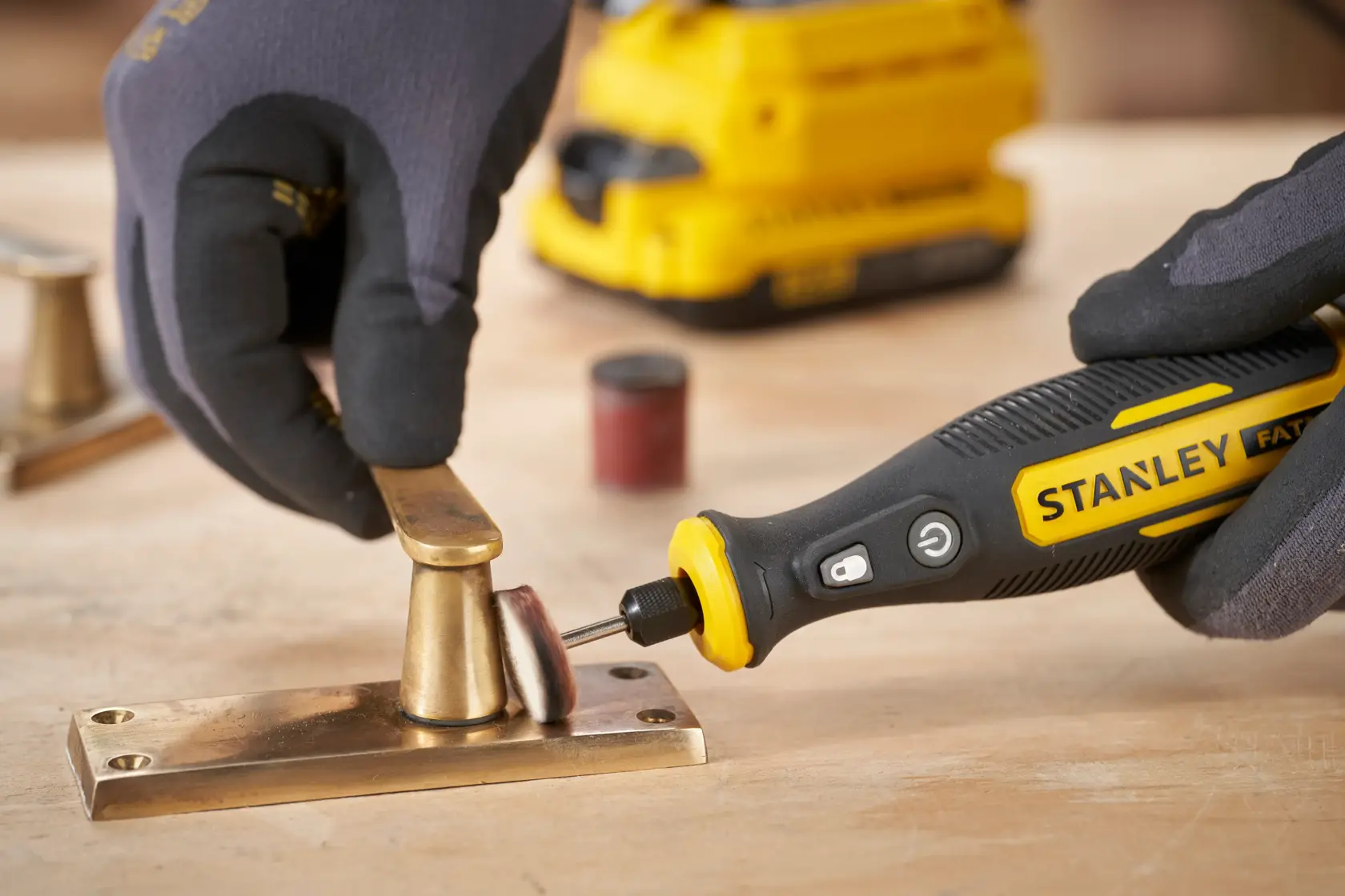 STANLEY SFMCE030B utensile rotante che lucida ferramenta in ottone su superficie di legno, foto ravvicinata.