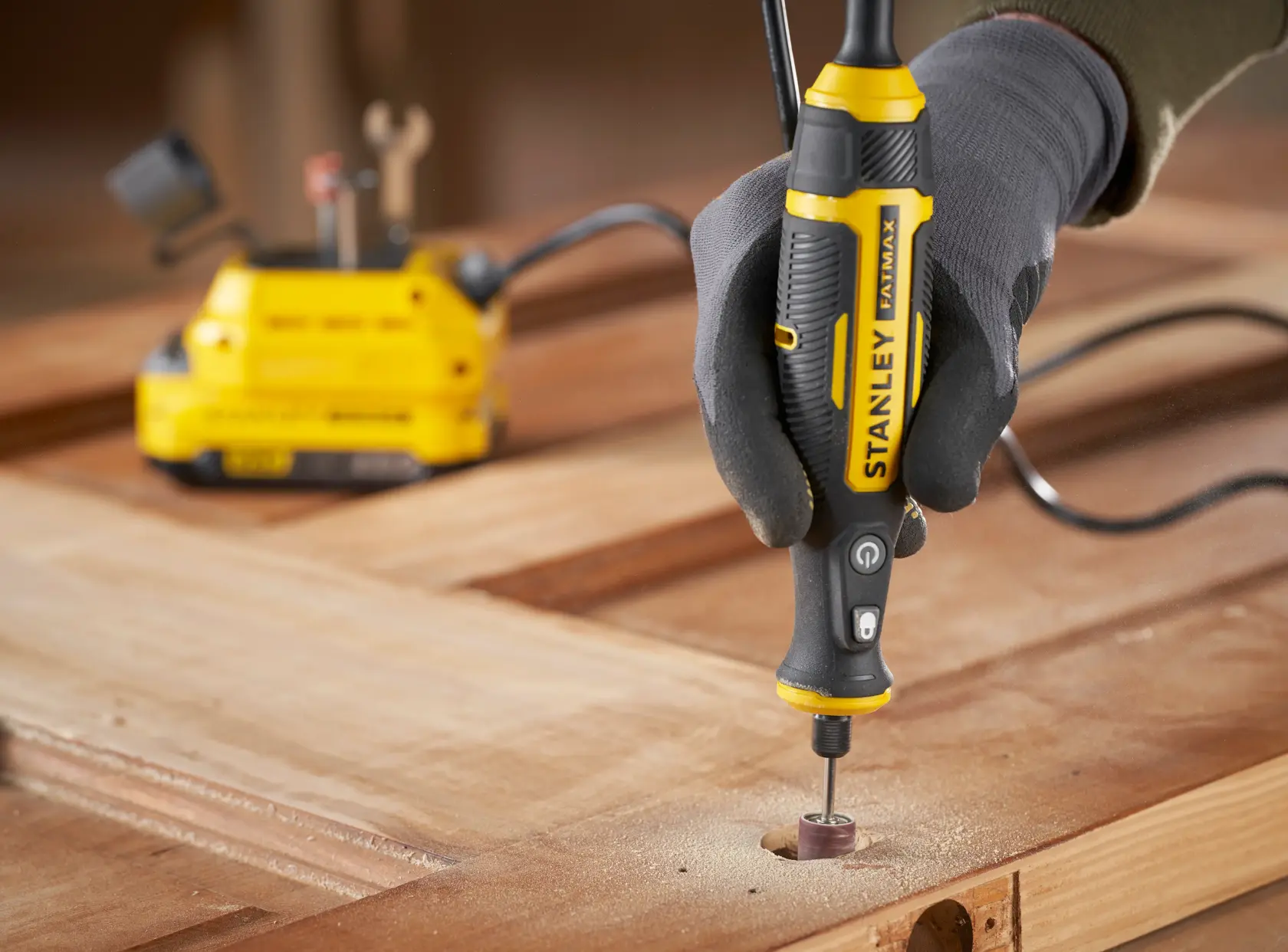 STANLEY SFMCE030B utensile rotante usato per levigare il legno, primo piano dello strumento in mano su superficie di lavoro.