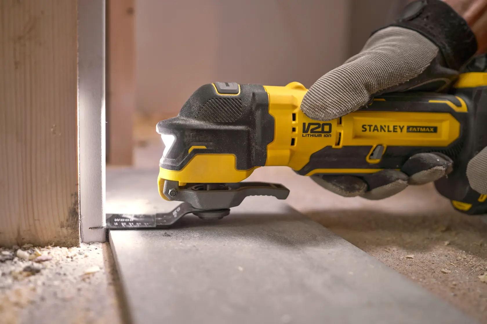 Stanley SFMCE510M2K outil multifonction oscillant coupant un panneau de sol, gros plan main gantée, chantier.