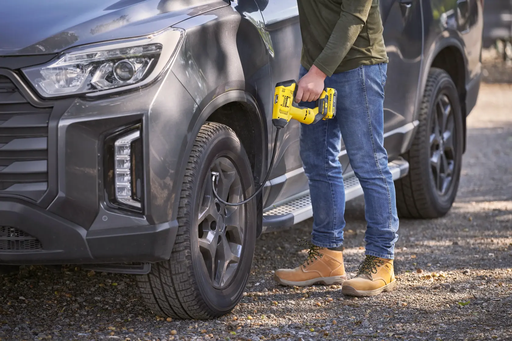 STANLEY SFMCE521B portable inflator being used to inflate a car tire outdoors.