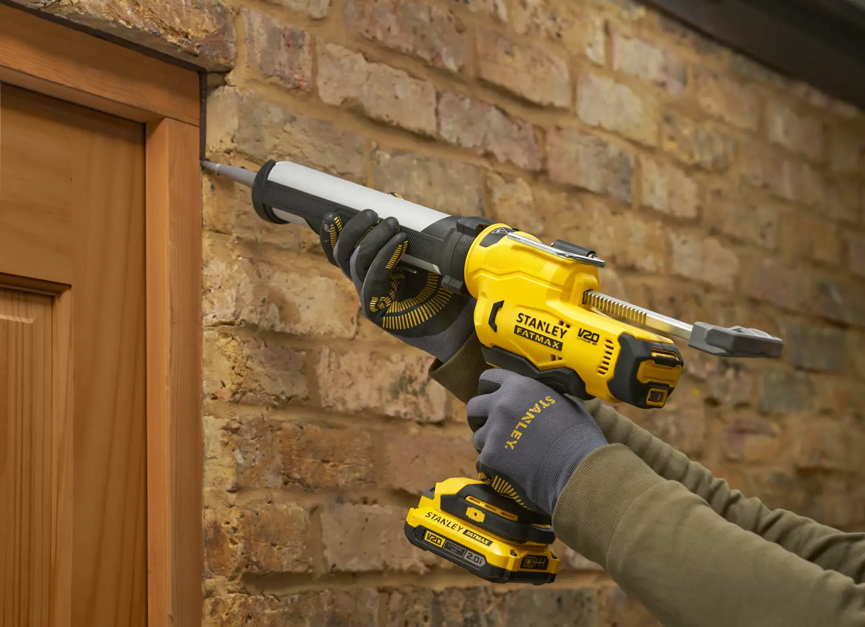 STANLEY SFMCE600B pistolet à calfeutrer utilisé pour sceller autour d’un cadre de porte en bois contre un mur en briques.