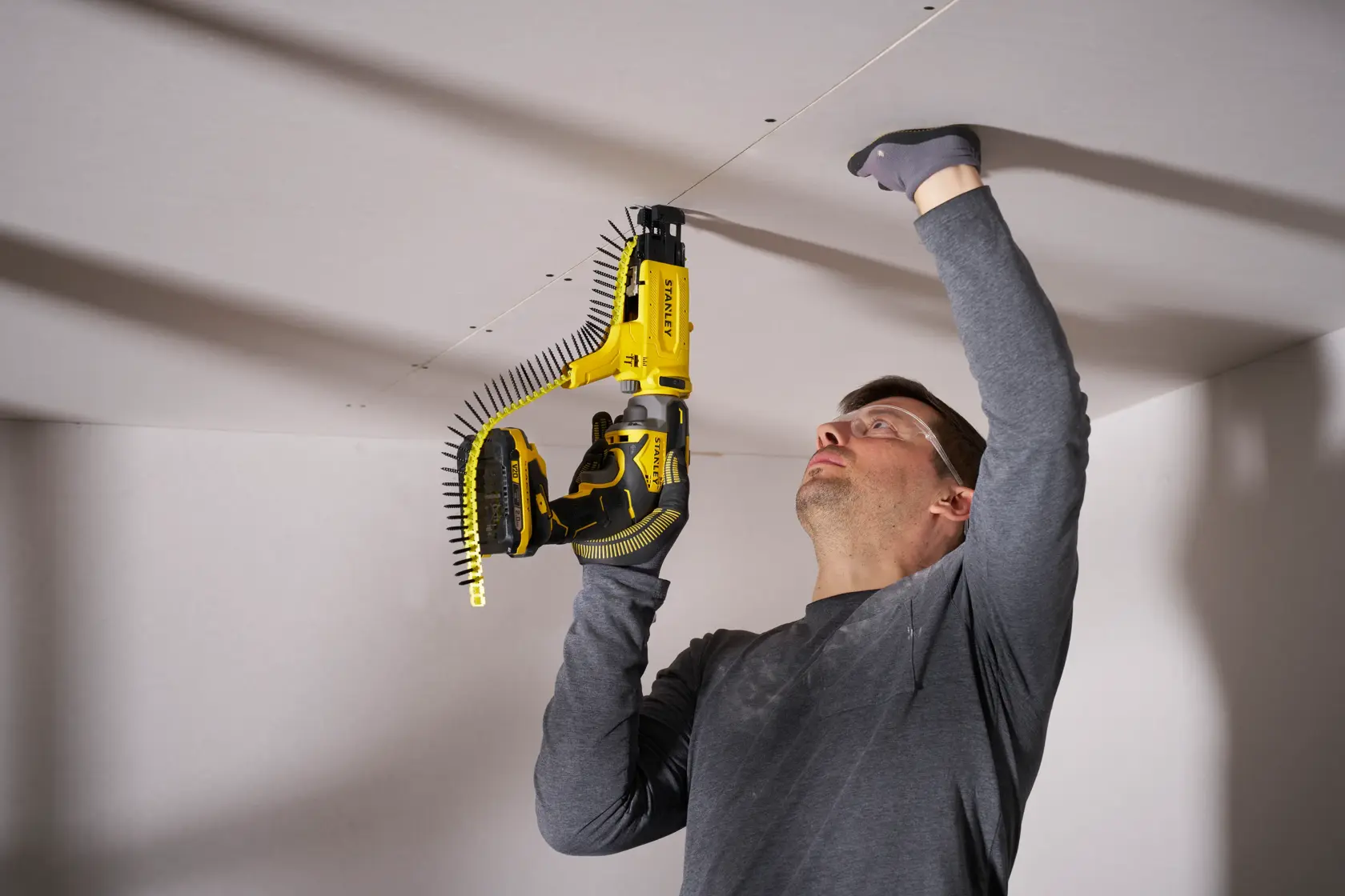 STANLEY SFMCF600B visseuse pour plaques de plâtre utilisée pour pose au plafond, angle frontal, outil jaune et noir.