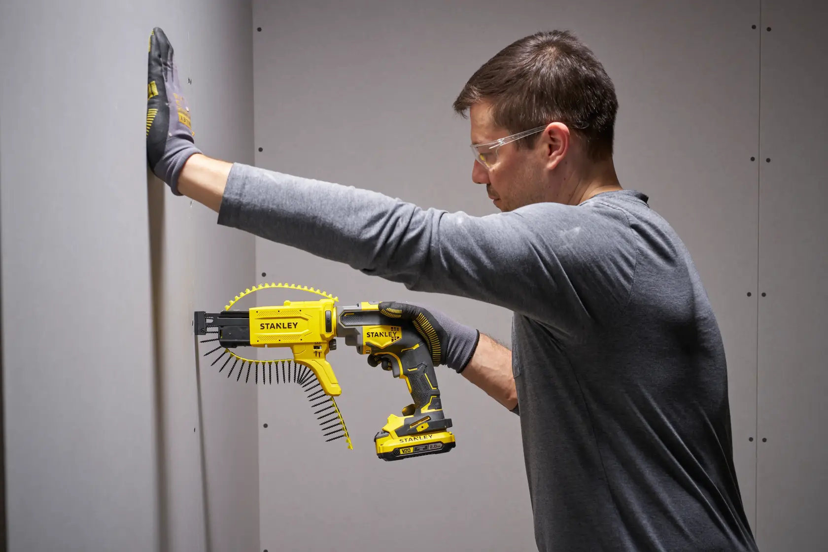 Photo de la visseuse autofeed STANLEY SFMCF600D1S utilisée pour installer des plaques de plâtre, tenue par une personne avec des gants.