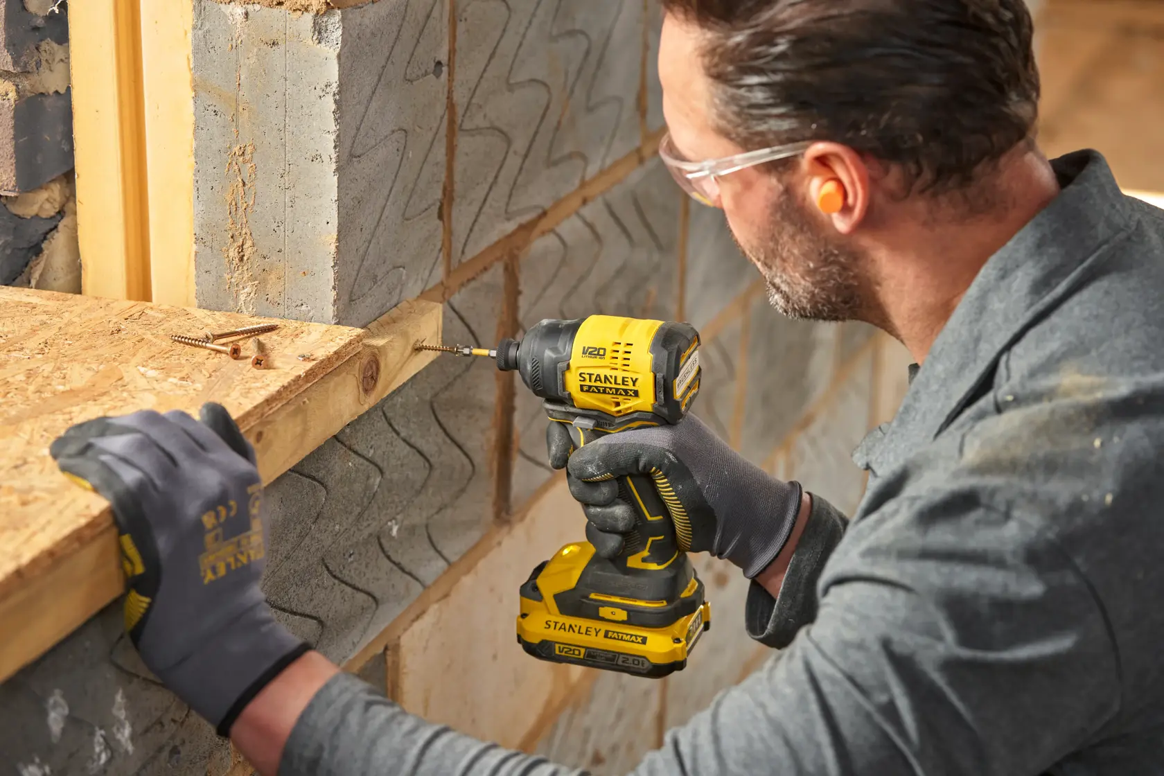 Photographie de la visseuse à chocs sans fil STANLEY SFMCF811D1T utilisée pour percer du bois sur un chantier.