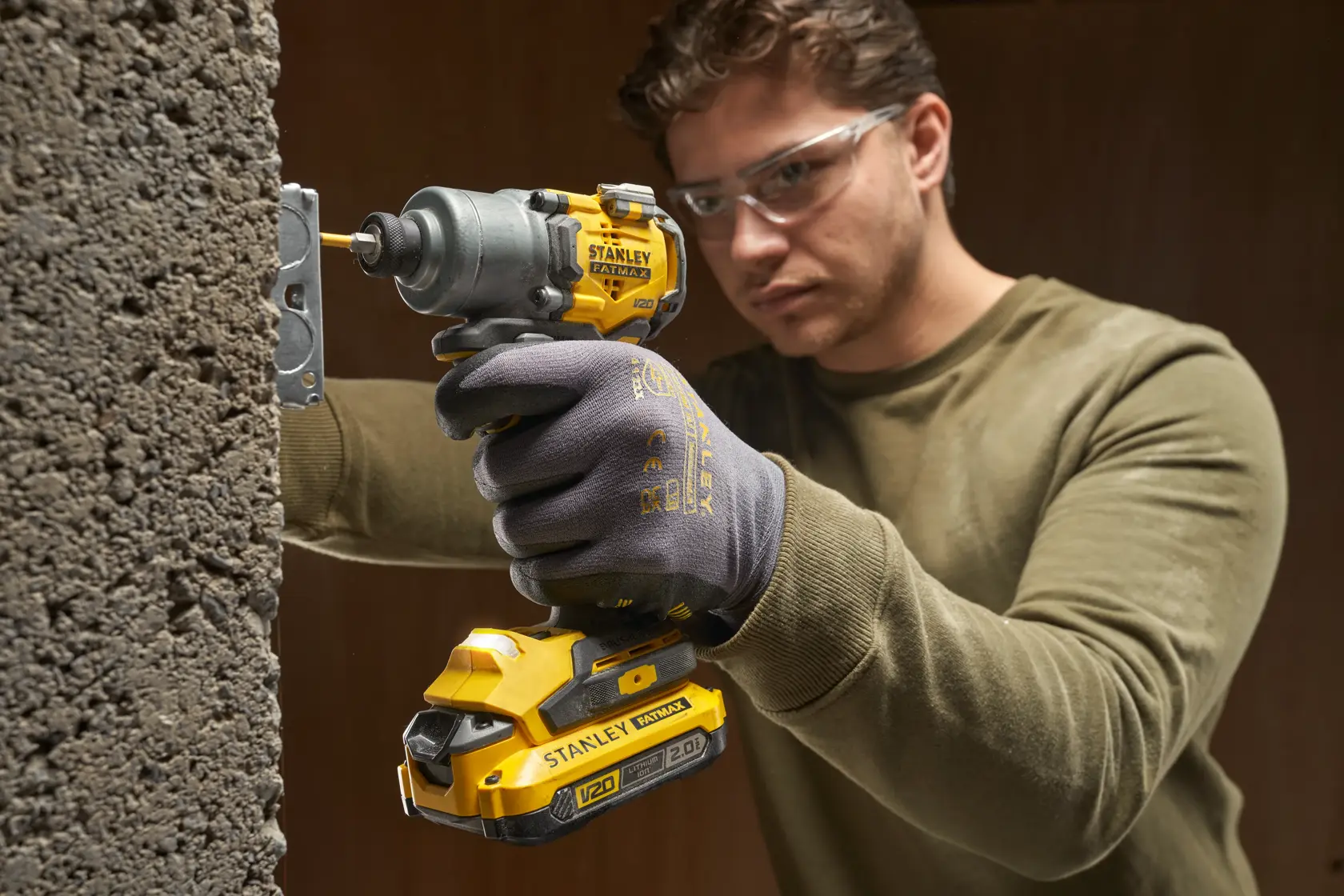 STANLEY SFMCF830B avvitatore a impulsi cordless giallo e nero in uso, fora un muro di cemento.
