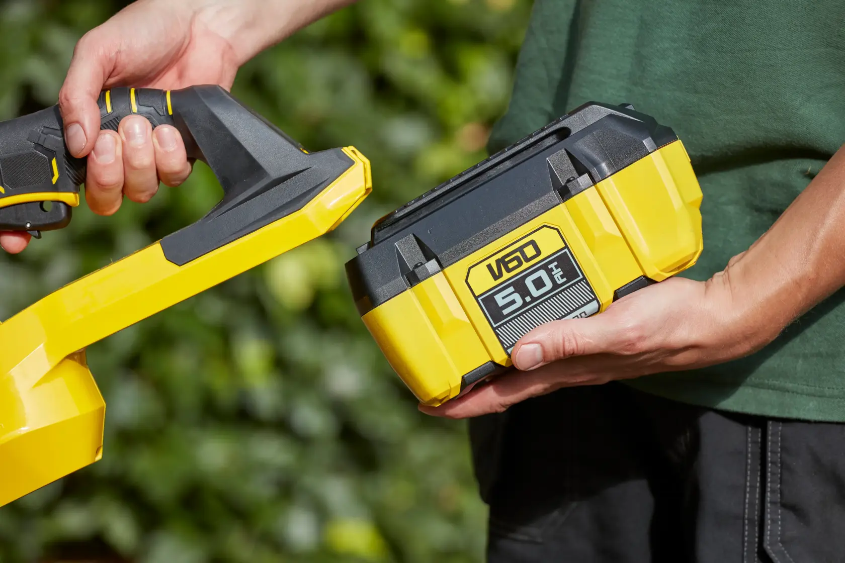 STANLEY SFMCHTB866B yellow and black V60 5.0Ah battery held near cordless tool outdoors