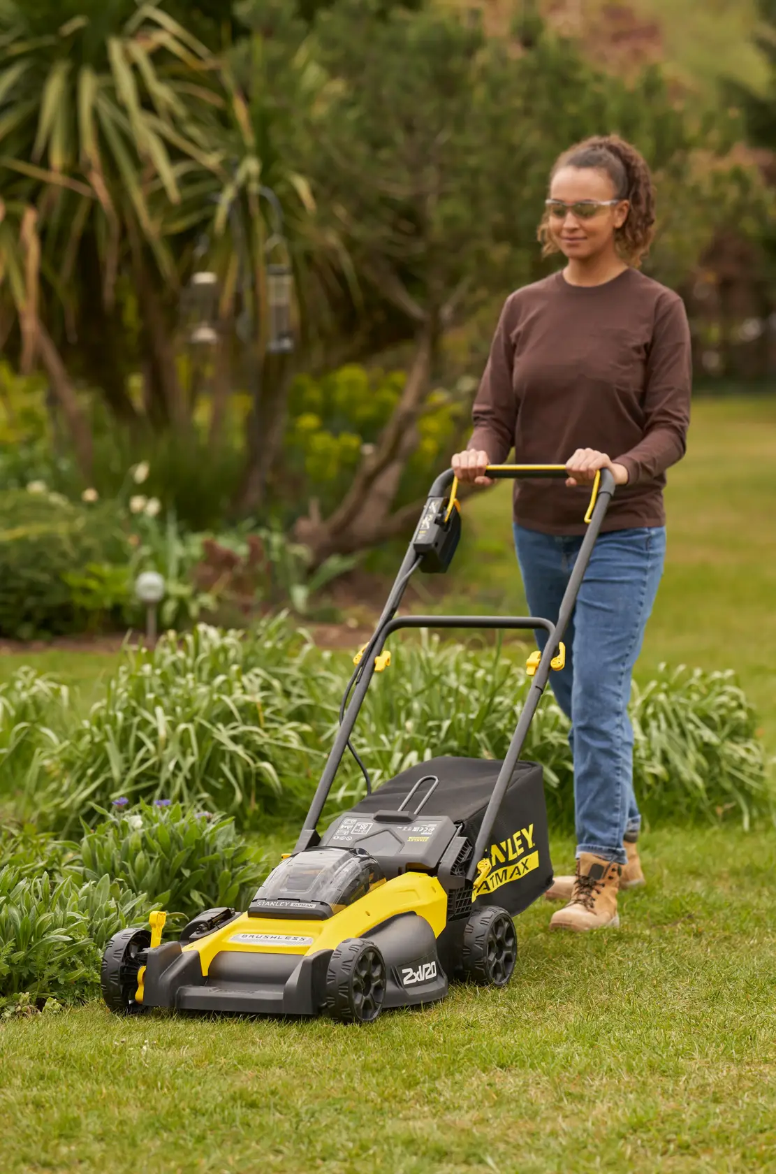 Side view of a STANLEY FATMAX cordless lawn mower in yellow and black with collection bag attached.