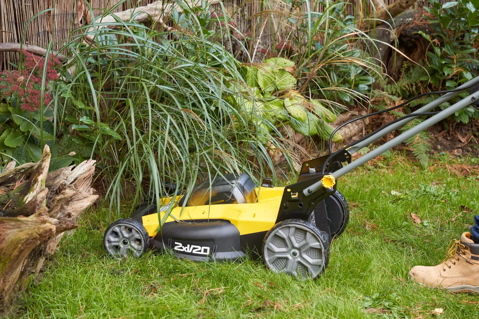 STANLEY SFMCMWS251M lawn mower side view cutting grass near plants outdoors.