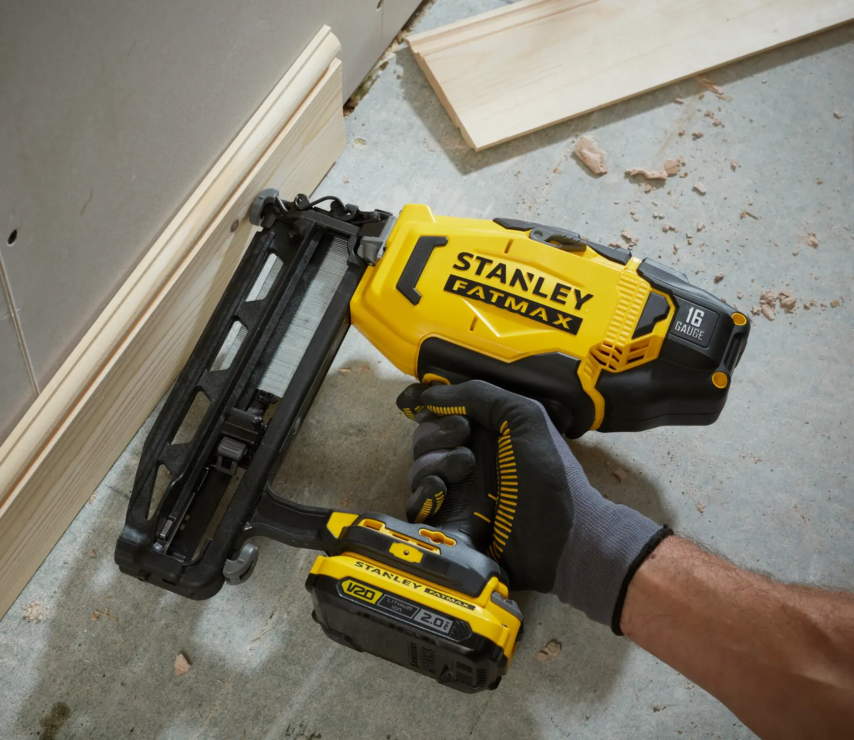 STANLEY SFMCN616D2K chiodatrice, gialla e nera, usata per installazione di battiscopa in legno, primo piano.