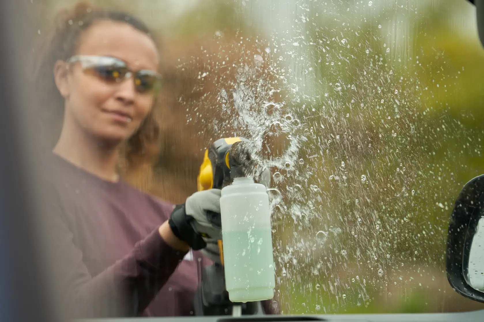 Yellow and black cordless pressure washer with long nozzle attachment, designed for portable outdoor cleaning tasks.