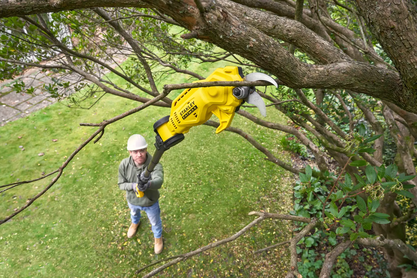 STANLEY SFMCPP632D1 potatore a batteria su asta gialla che taglia rami d'albero in giardino.