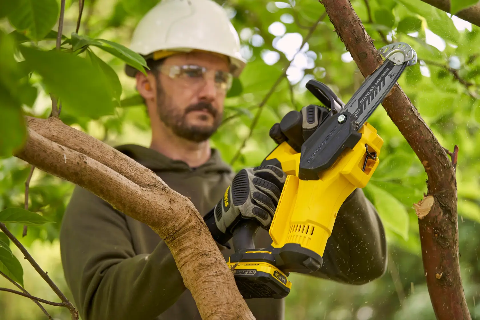 Motosega compatta a batteria Stanley SFMCPS415D1 che taglia un ramo d'albero all'aperto.