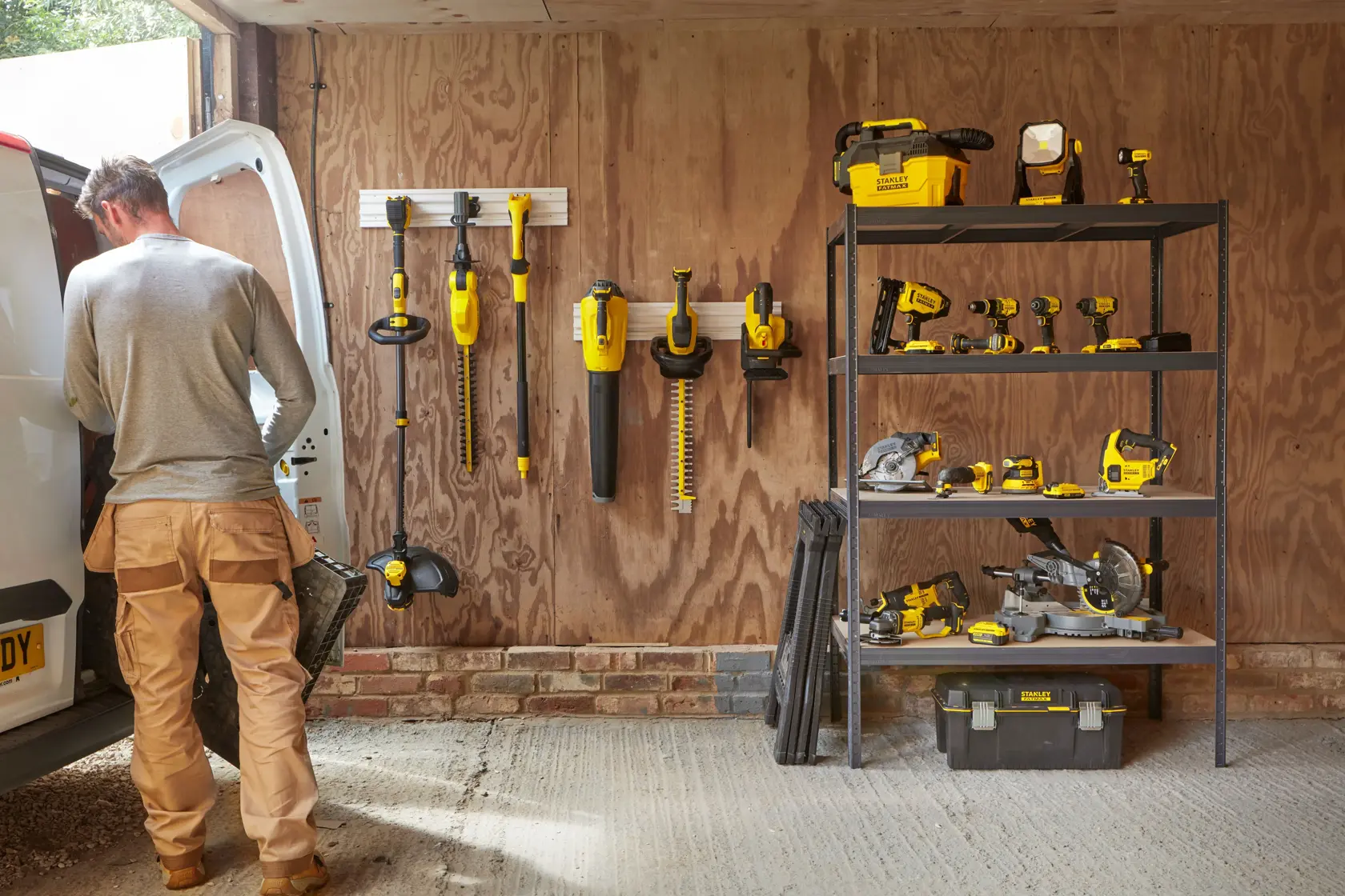 Outils électriques et accessoires STANLEY SFMCPS620B organisés dans un garage, étagères et rangement mural visibles.