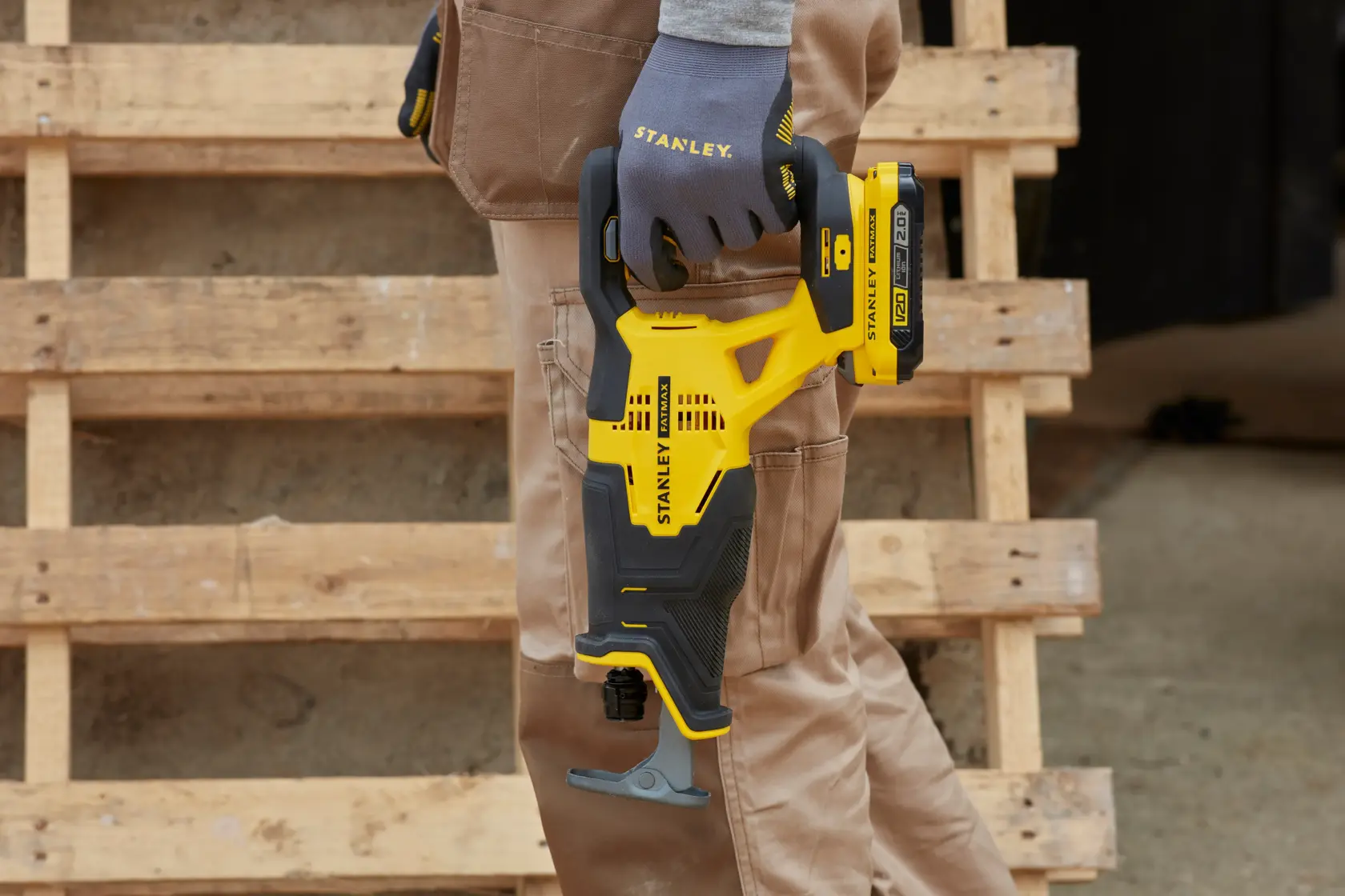 STANLEY SFMCS300D2K sega reciproca senza fili tenuta da una mano con guanto, design giallo e nero, ambiente esterno.