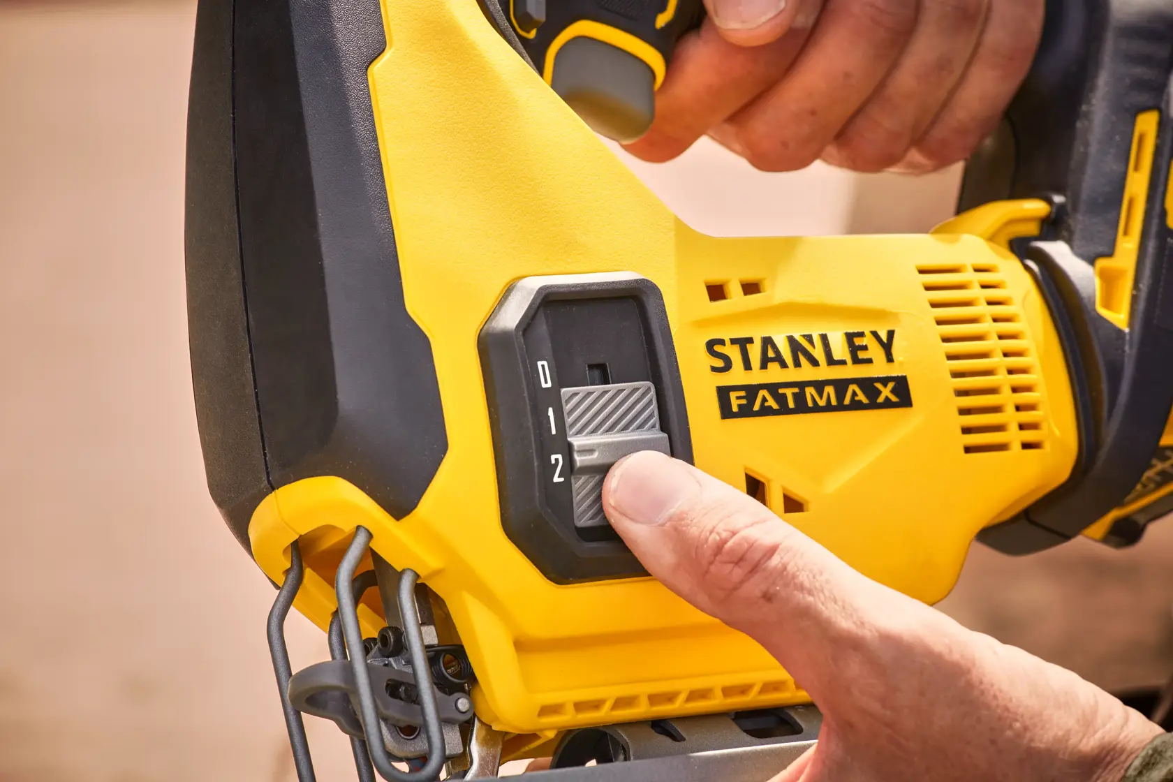 Foto dell'interruttore di controllo velocità del seghetto STANLEY SFMCS600M2K regolato, utensile giallo e nero in primo piano.