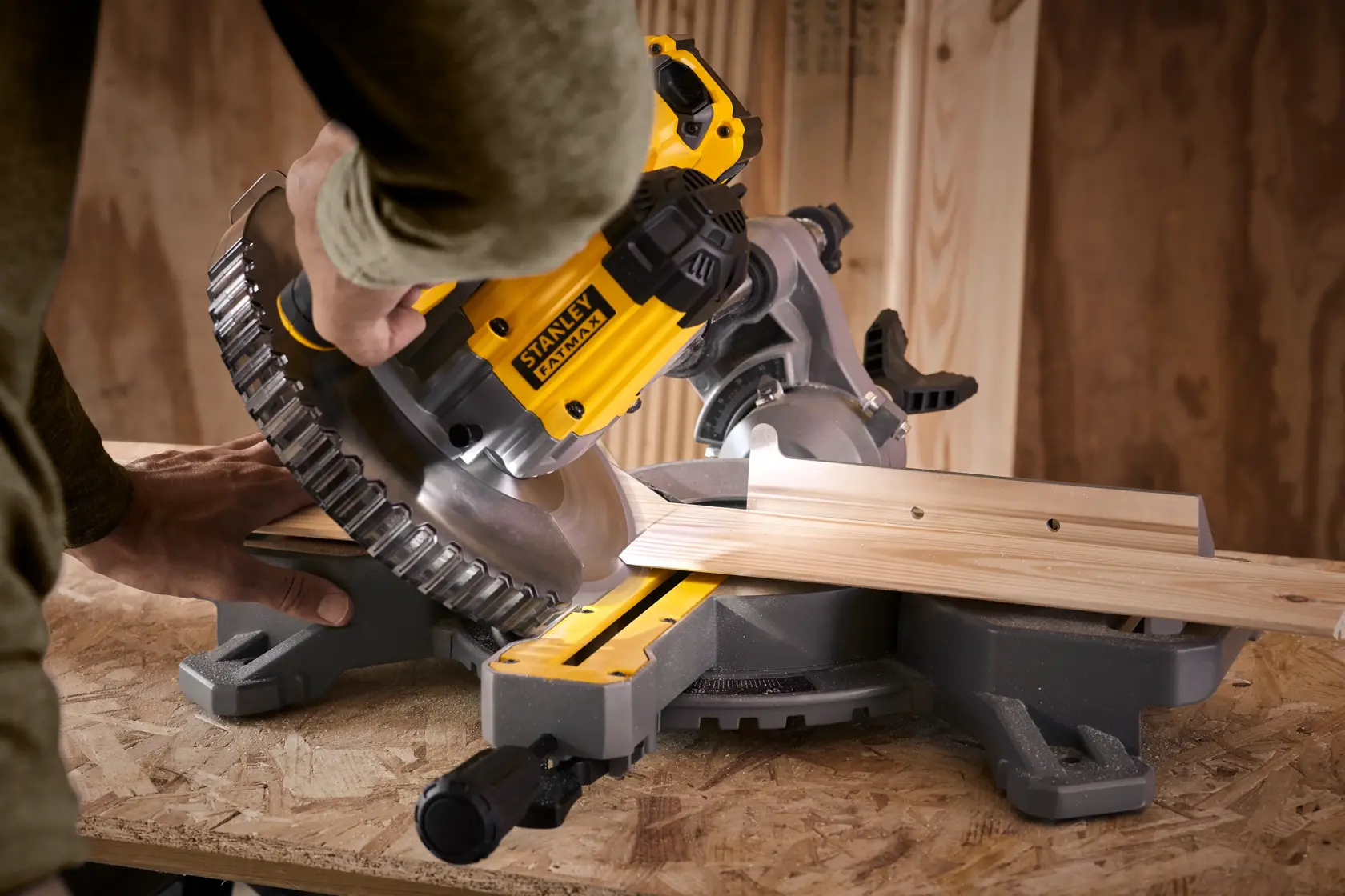 STANLEY SFMCS701M1 miter saw cutting wood, close-up angled view, yellow and black tool on workbench.