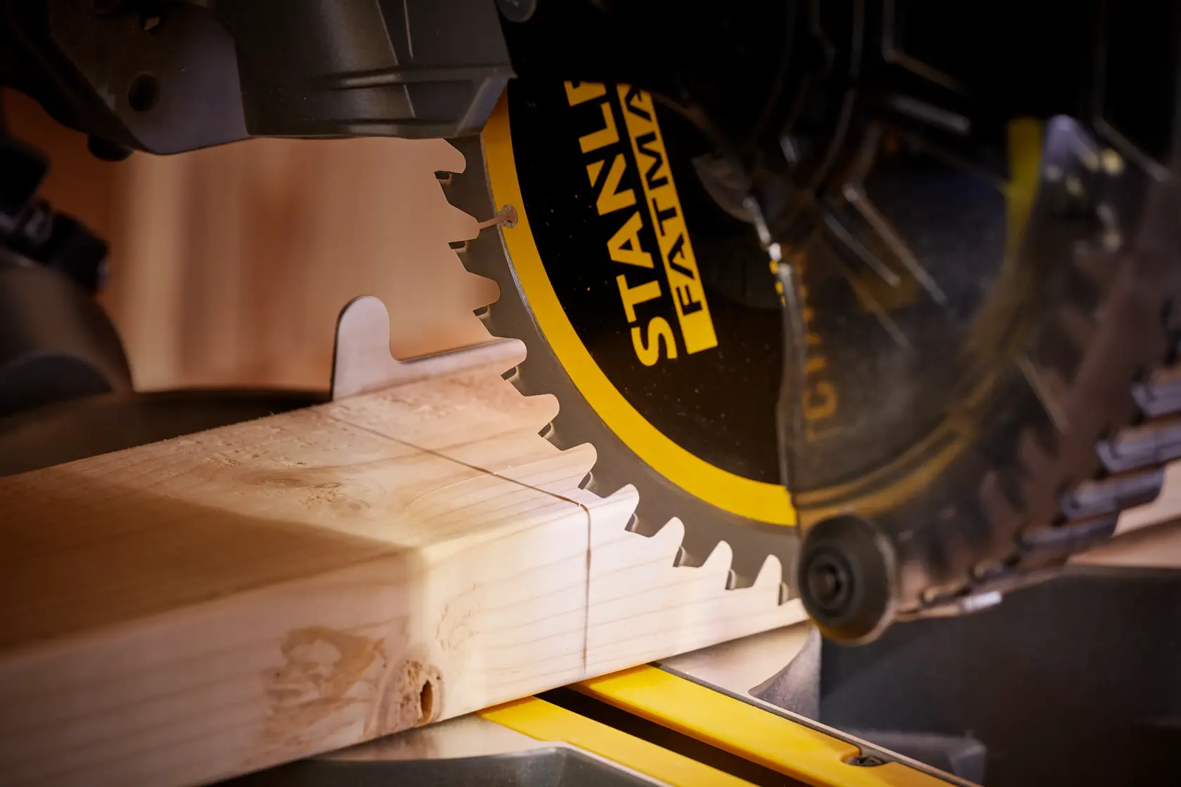 STANLEY SFMCS701M1 miter saw close-up cutting wood, black and yellow blade, woodworking context.