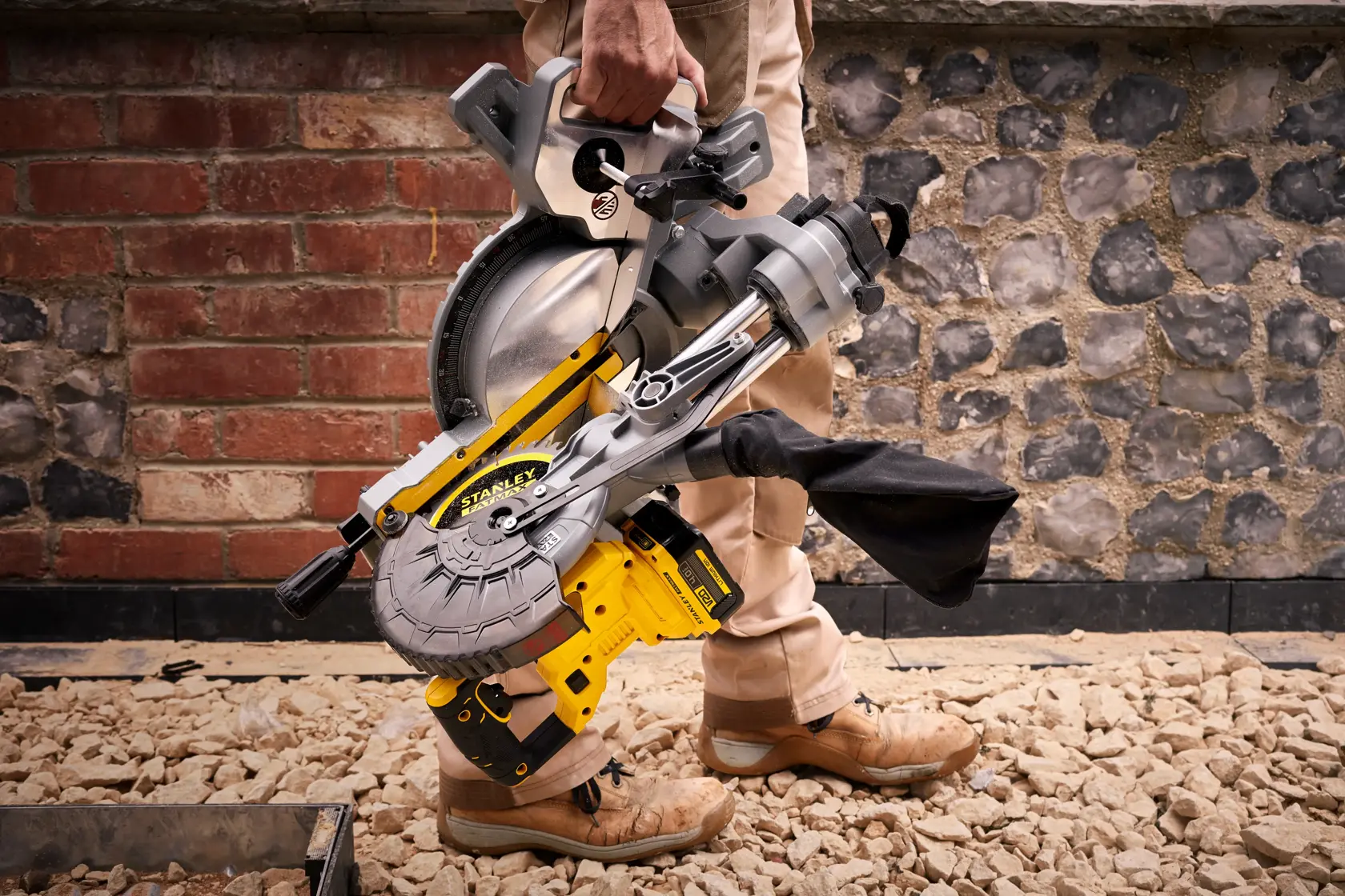STANLEY SFMCS701M1 scie à onglet jaune et argent, portée à la main sur un chantier.