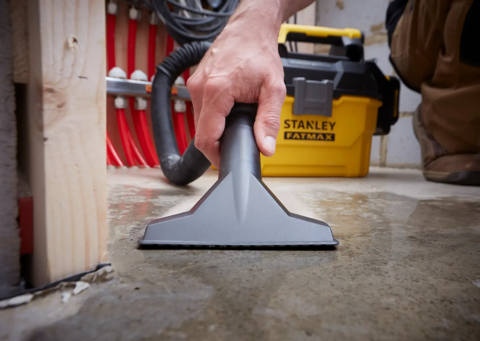 STANLEY SFMCV002B Nass- und Trockensauger im Einsatz auf nassem Boden, Nahaufnahme der Düse und gelben Einheit.